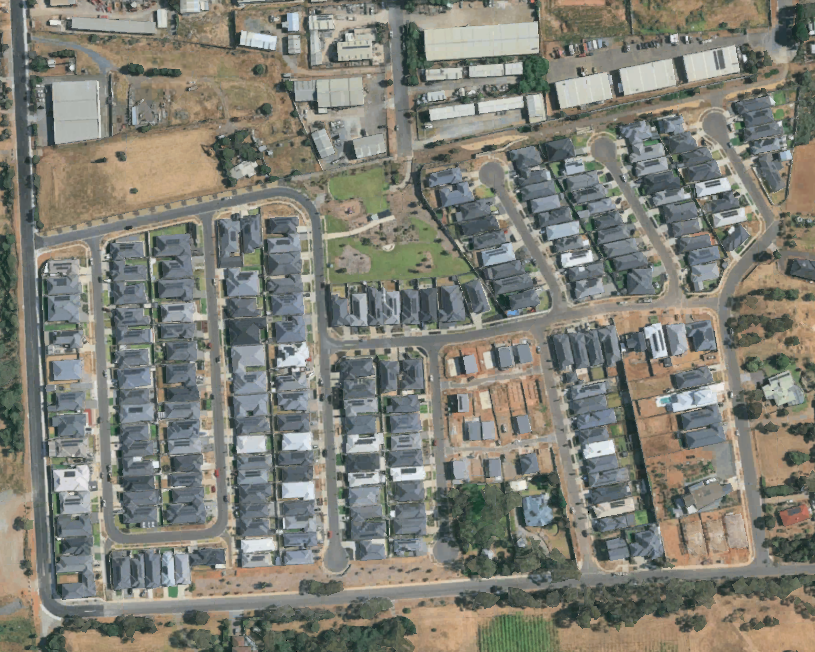Aerial view of a residential neighborhood with houses, streets, and some open green spaces.