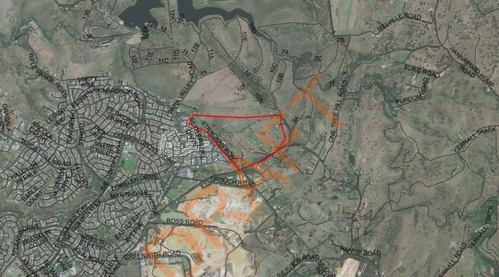 A map showing streets and roads of a town, with a red boundary marking a specific area, and orange shaded regions indicating zones of interest or development.