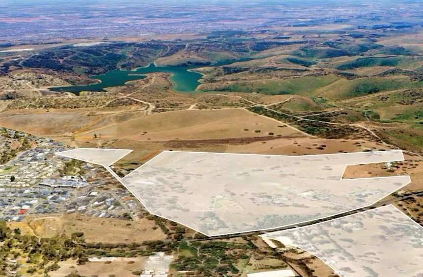 Aerial view of a landscape with hills, water bodies, and open land, including a large outlined area likely indicating property boundaries.