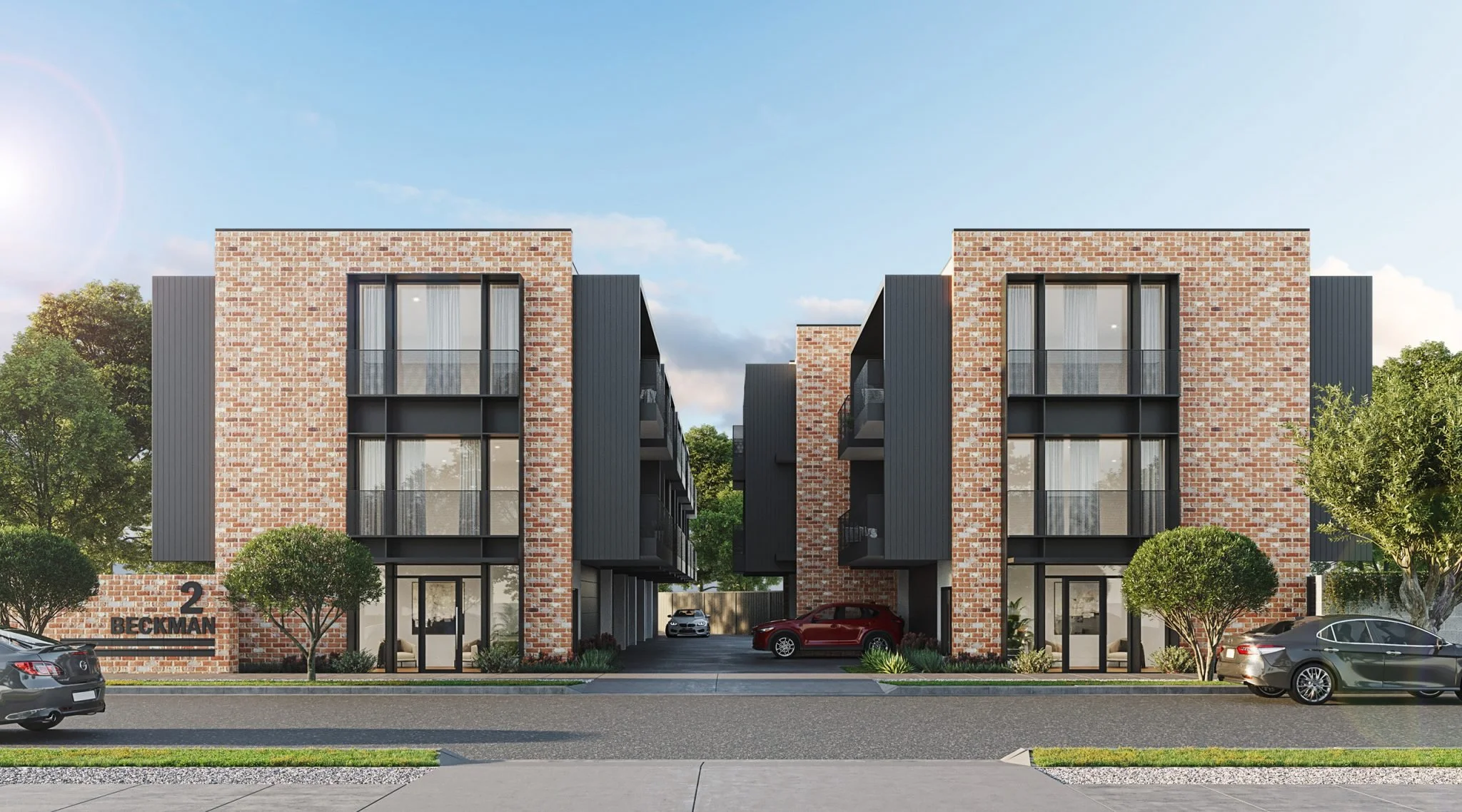 A modern residential building with brick facade and black accents, featuring three floors, large windows, and balconies. The building is labeled with the address "2 Beckman" on the left side. Several cars are parked in front, and small trees with trimmed bushes are along the sidewalk under a blue sky with some clouds.