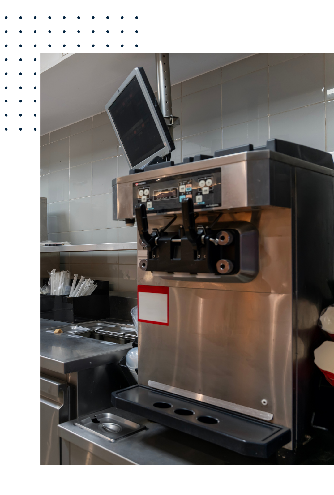 Commercial ice cream or frozen beverage machine with digital display screen and dispensing handles, placed on a stainless steel counter in a kitchen or food service setting.