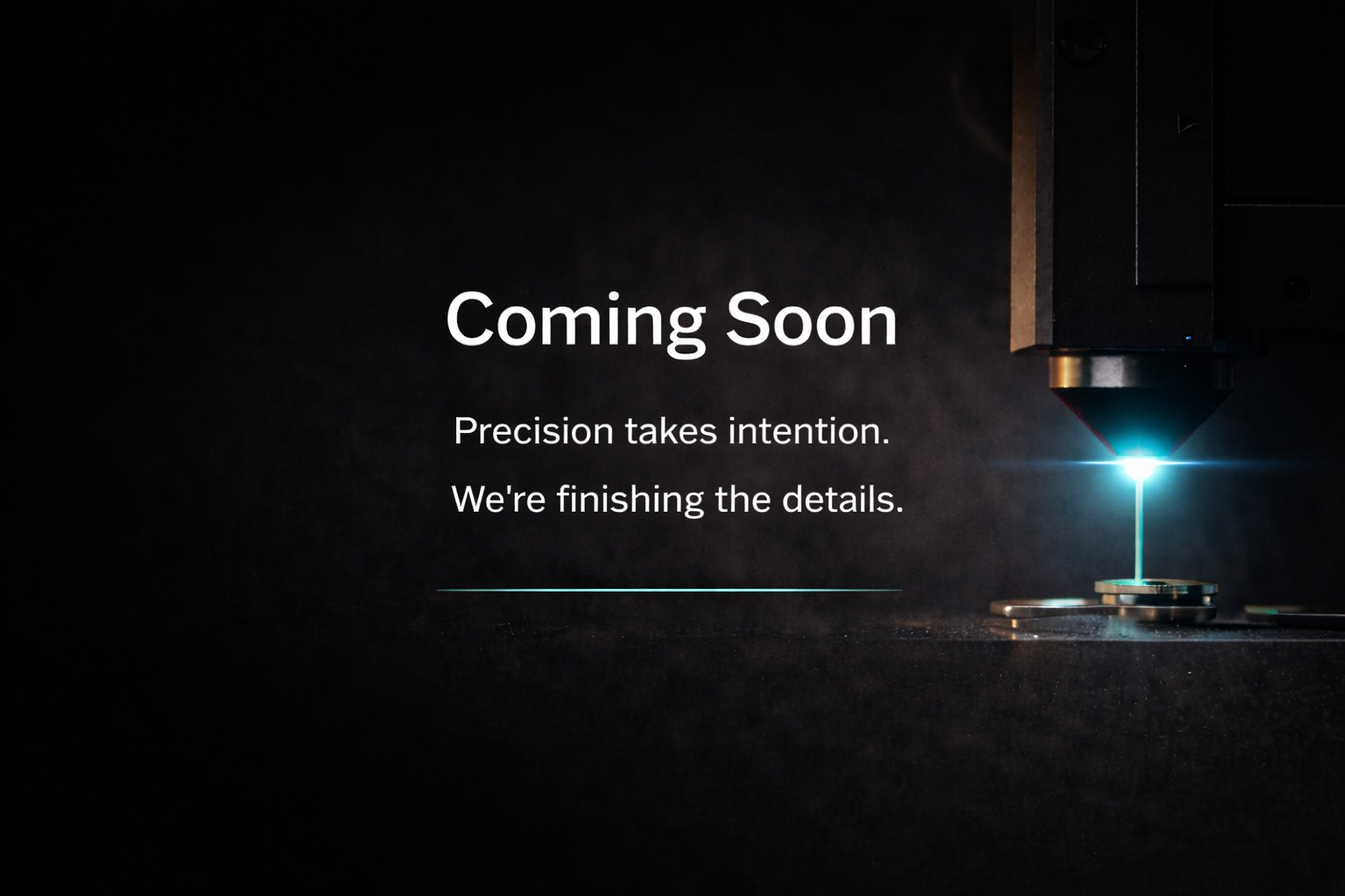 A dark background with a laser cutter on the right side and the text 'Coming Soon. Precision takes intention. We're finishing the details.' on the left side.