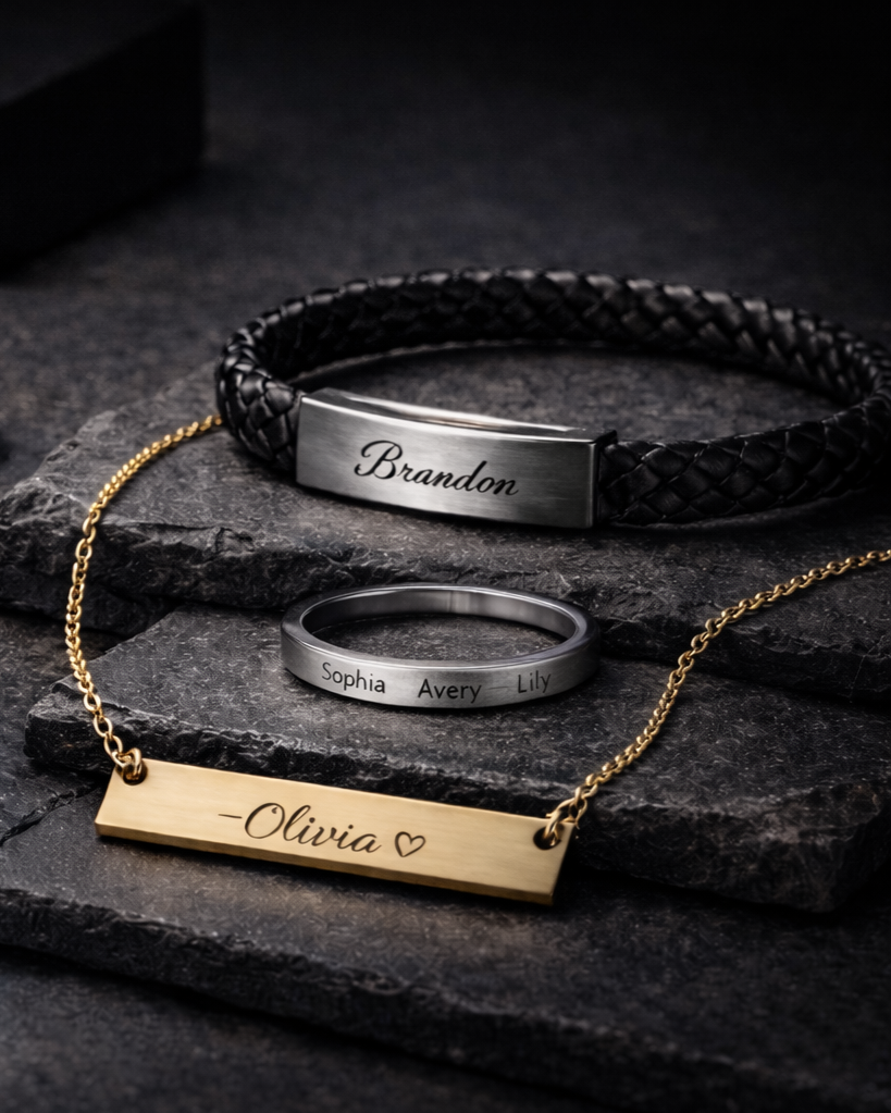 Three personalized jewelry pieces on black textured surfaces: a black braided leather bracelet with a silver nameplate engraved 'Brandon,' a silver ring engraved with names 'Sophia, Avery, Lily,' and a gold necklace with a rectangular pendant engraved '-Olivia' with a heart.