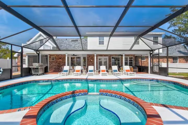 A pool and hot tub with lounge chairs