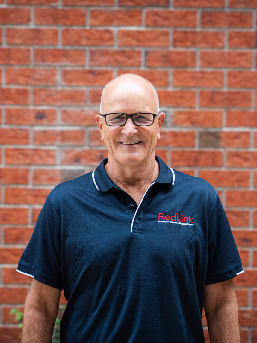 A smiling woman with curly black hair, wearing glasses, hoop earrings, layered necklaces, and a striped blouse.