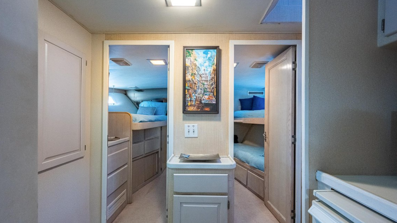 View of a small bedroom with two sets of bunk beds on each side and a framed painting of a street scene in the center.