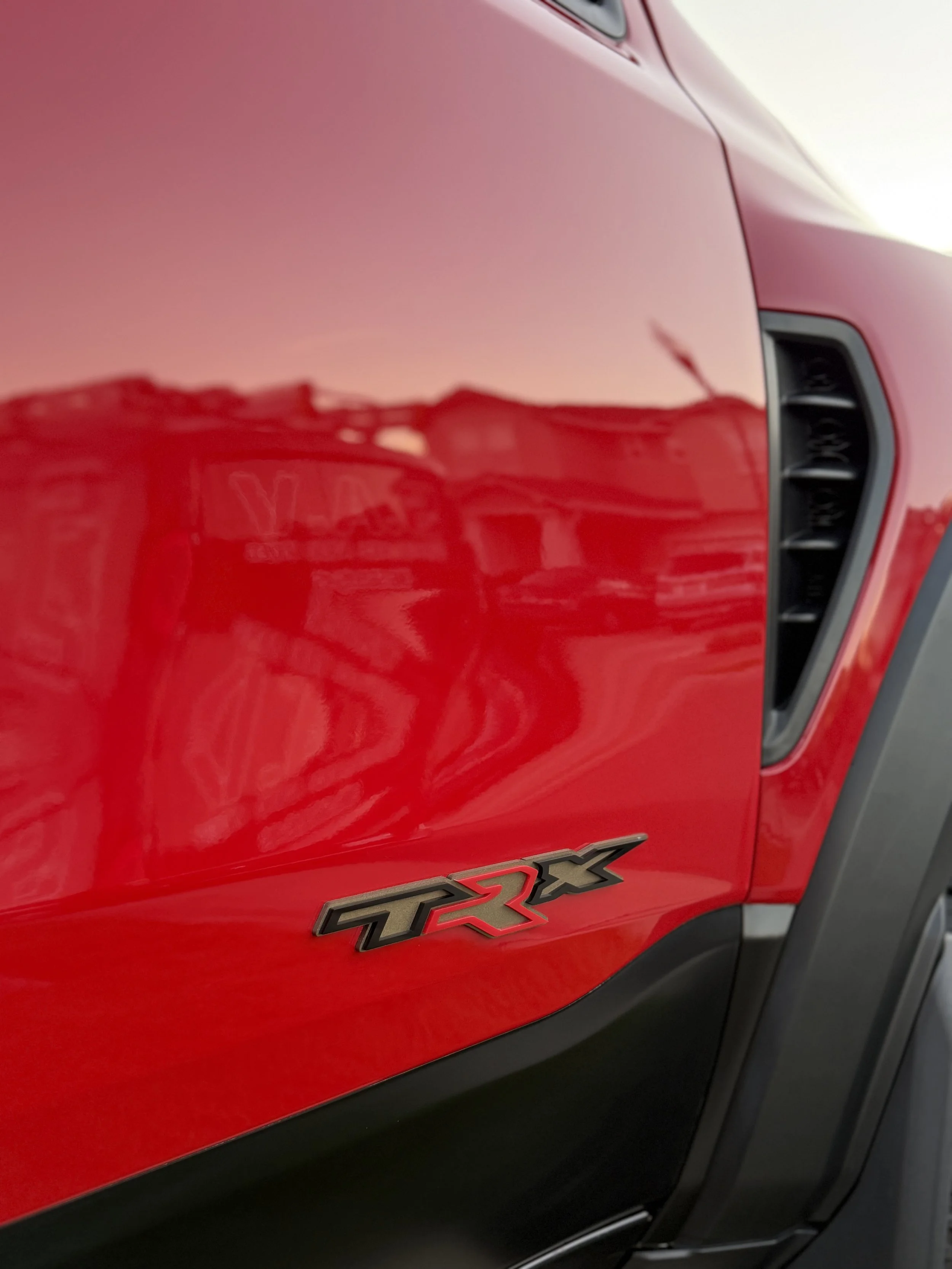 Close-up of a red vehicle's side with a 'TRX 4X' badge.