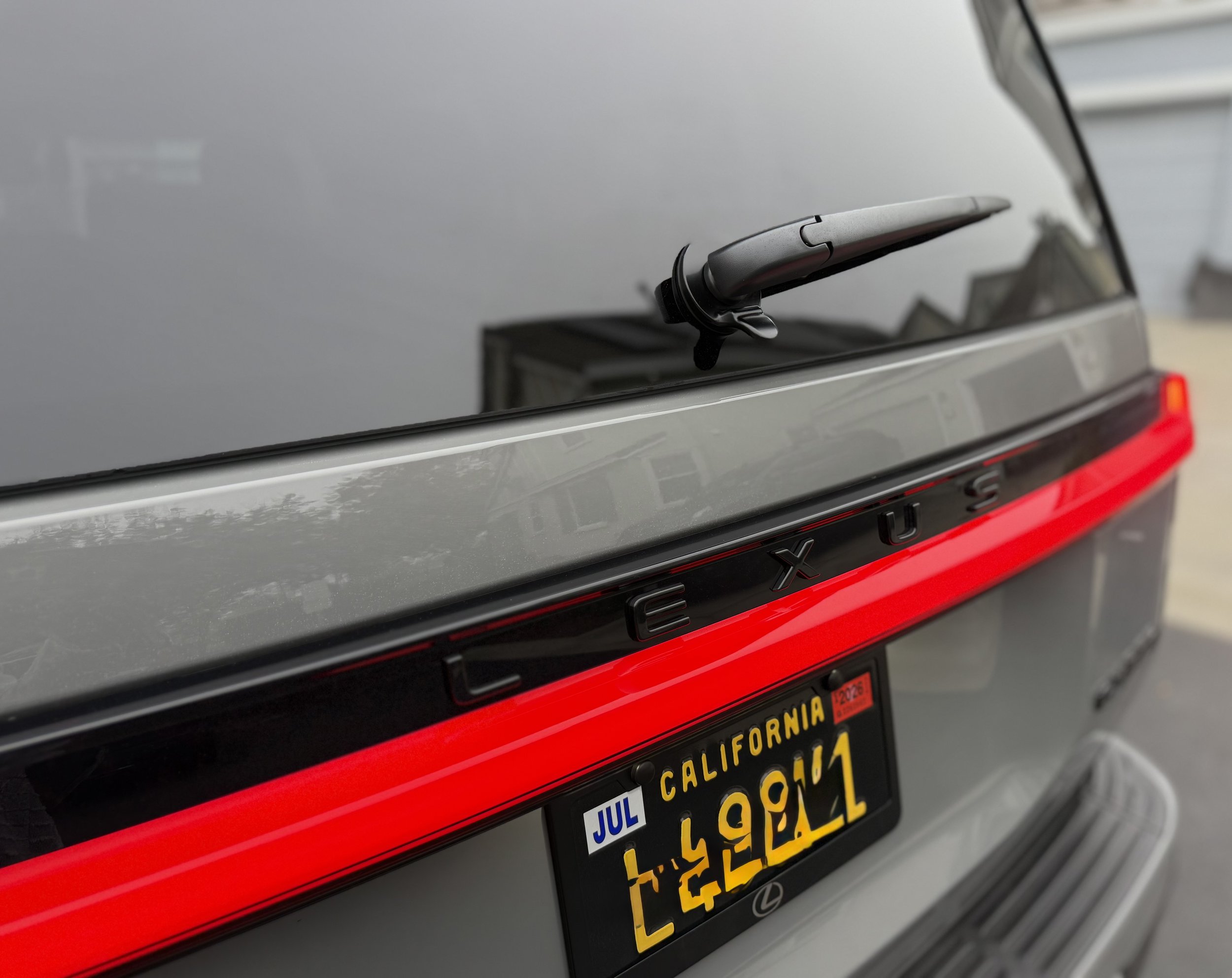 Close-up of the rear of a silver Lexus SUV with a California license plate and a red light strip across the back.