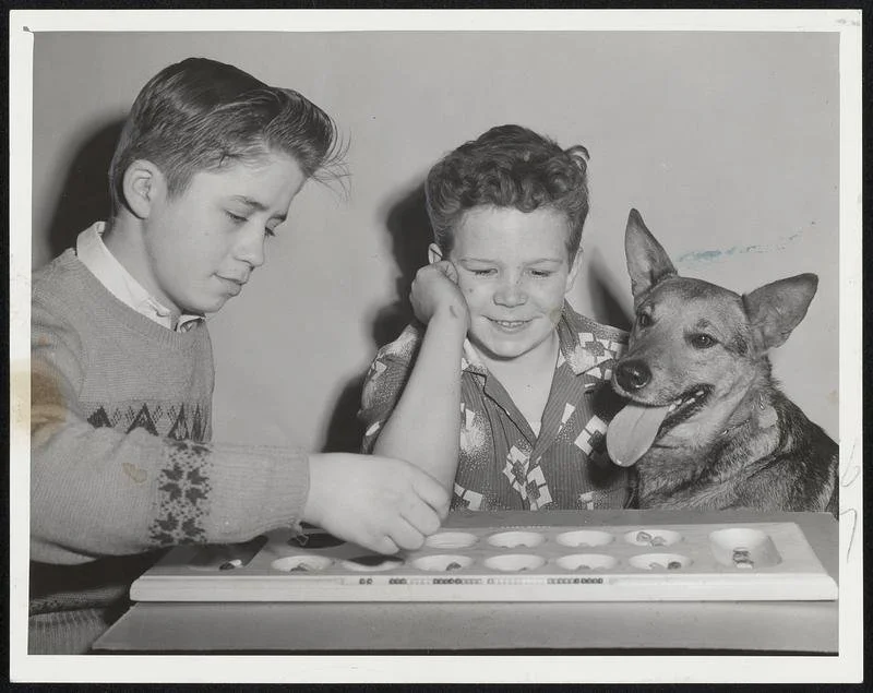 Enjoying Fast Game of Kalah are Louis Cijan, 13, of 18 Upton St., South End, a student at the Rice School, and Joey Ernshaw, 13, of 721 Tremont St., South End. Feb. 1957. 