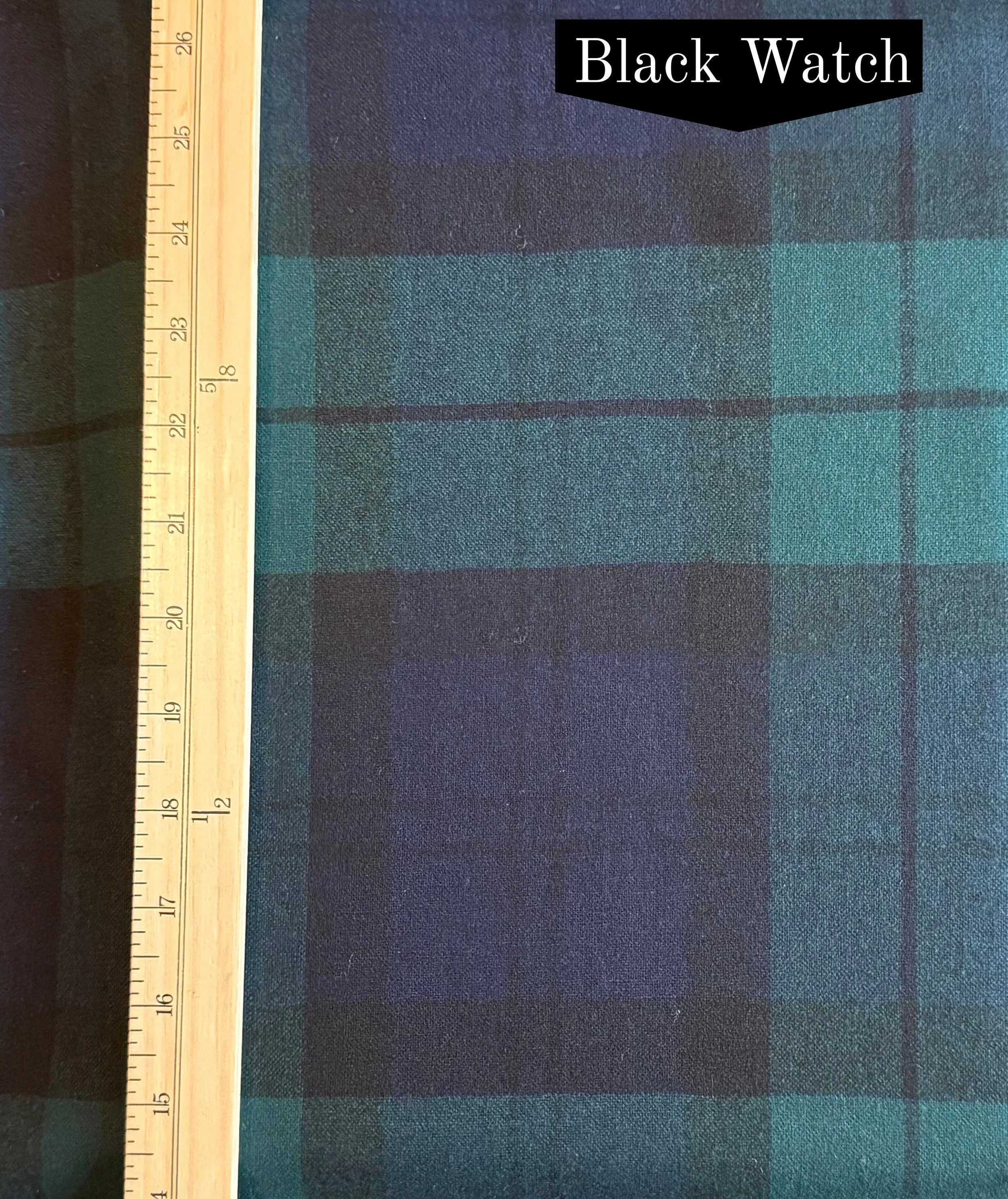 Black Watch tartan, blue and green plaid wool fabric with a vertical ruler on the left side of the photo.