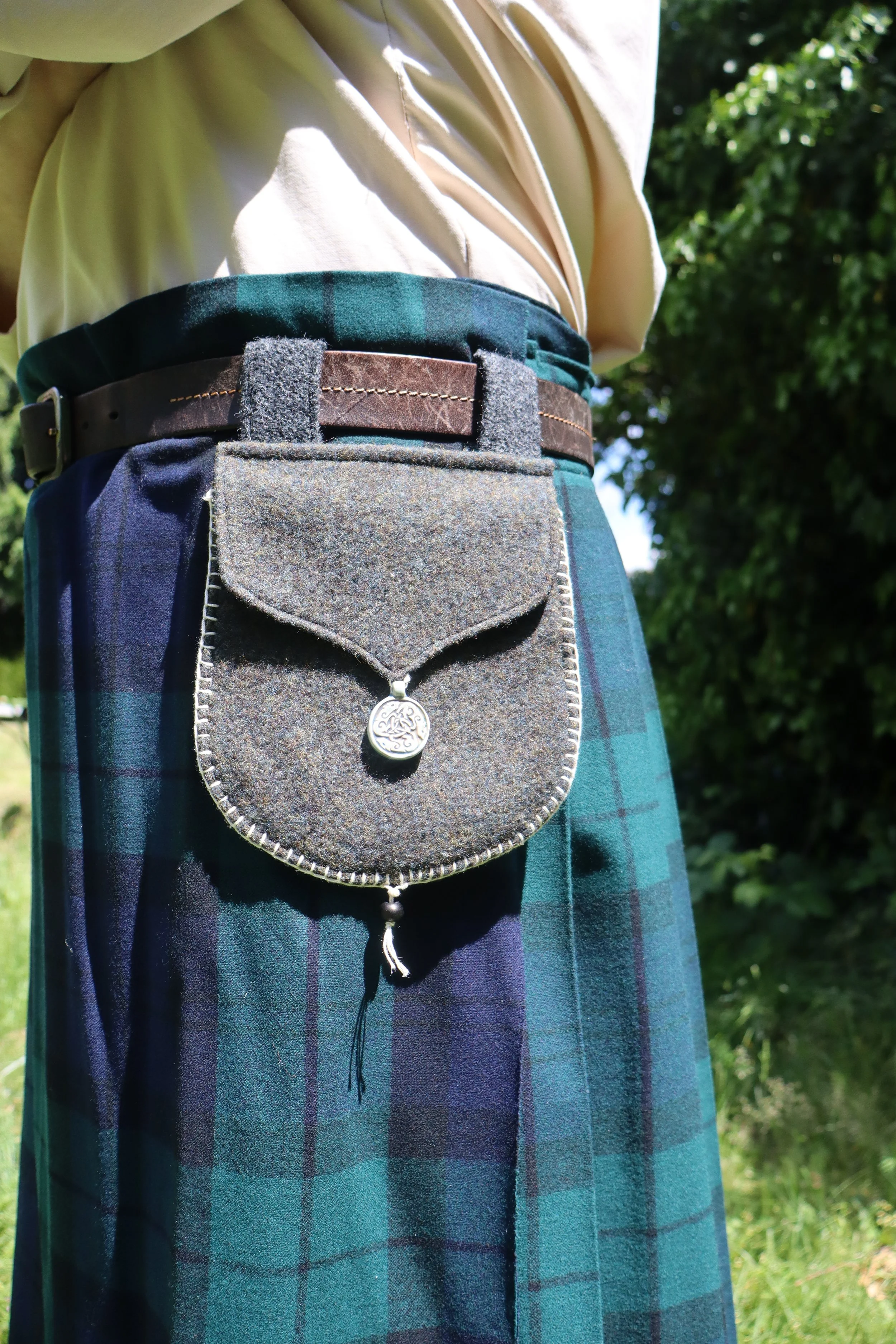 Grey Wool Bag with round clay clasp on a person's belt
