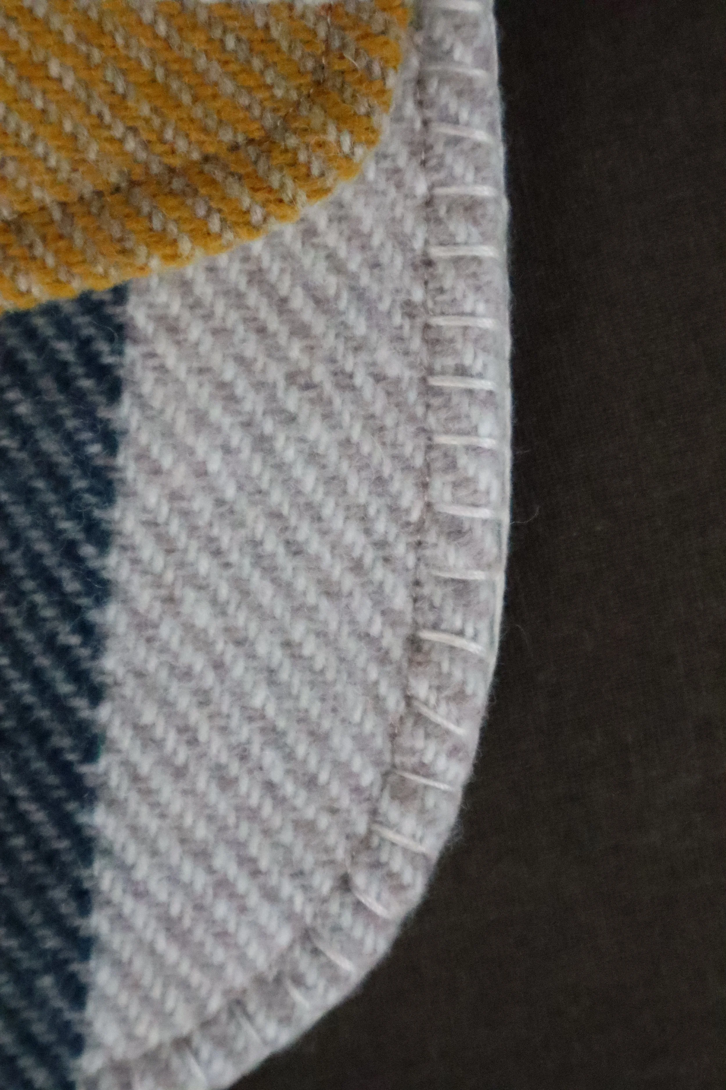 Close up of Tan and multicolor Wool Bag with bone clasp handstitching