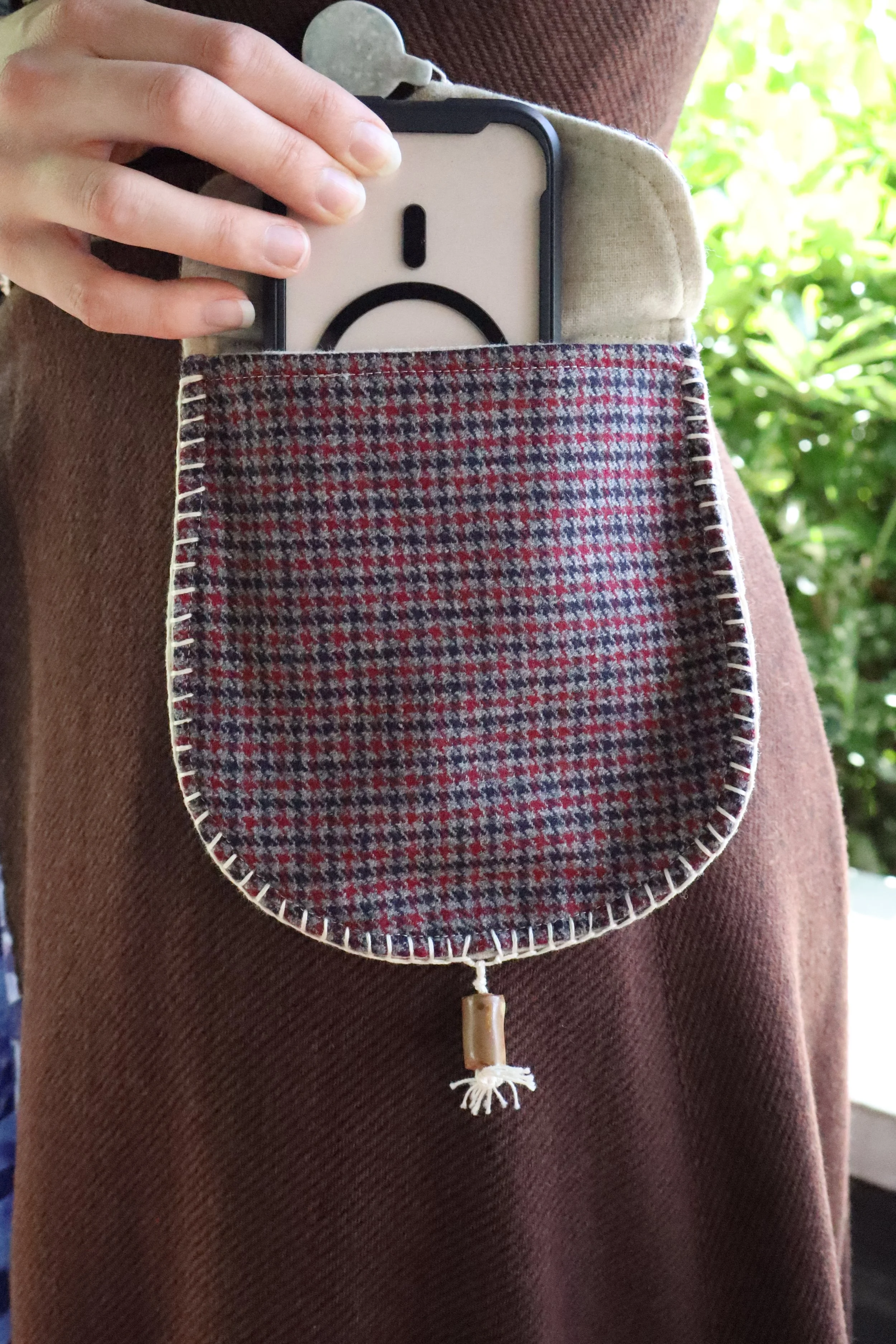 Blue and Red houndstooth belt pouch with a cell phone being taken out of it