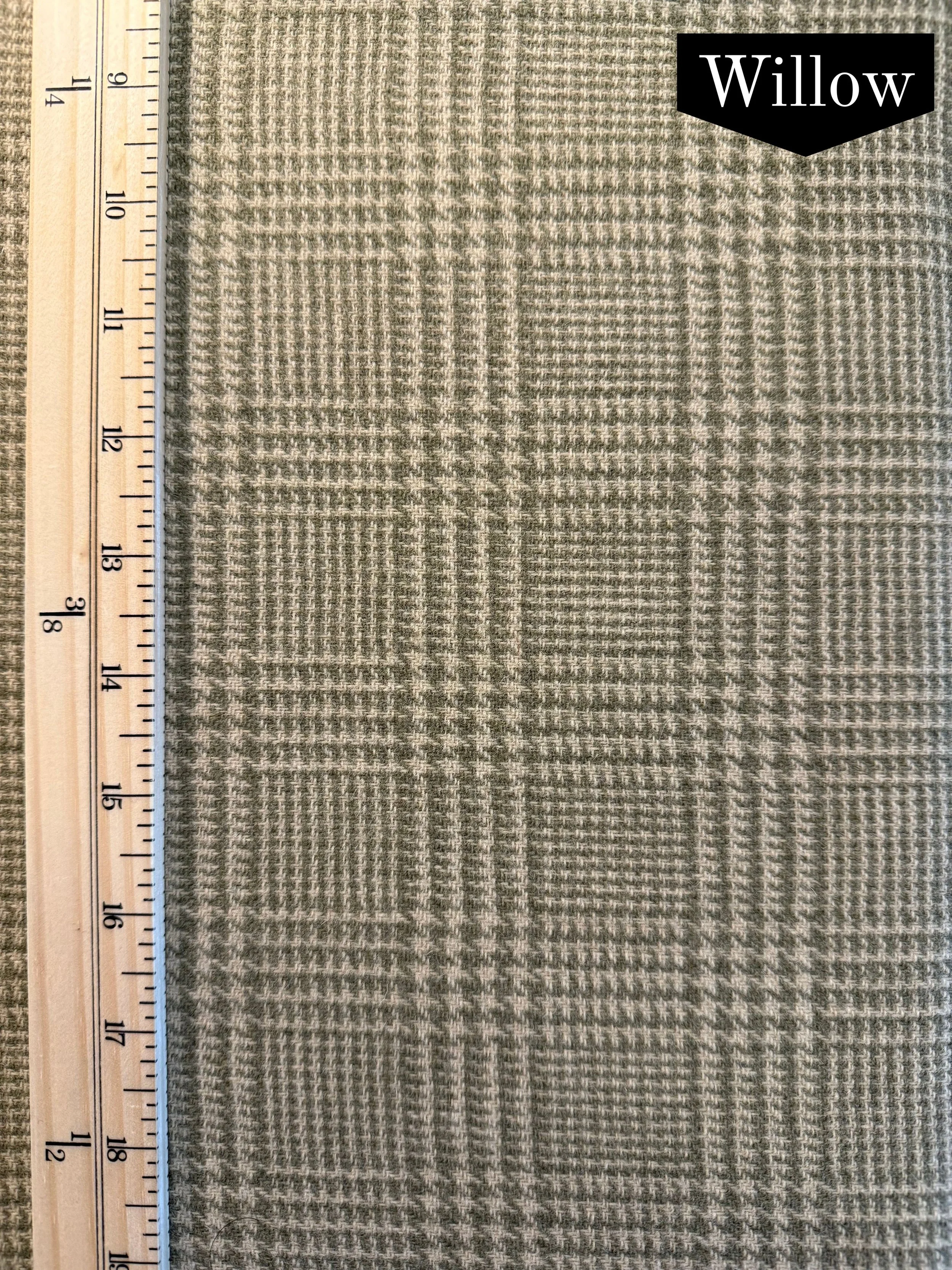 green and beige houndstooth plaid wool fabric with a vertical ruler on the left side of the photo.