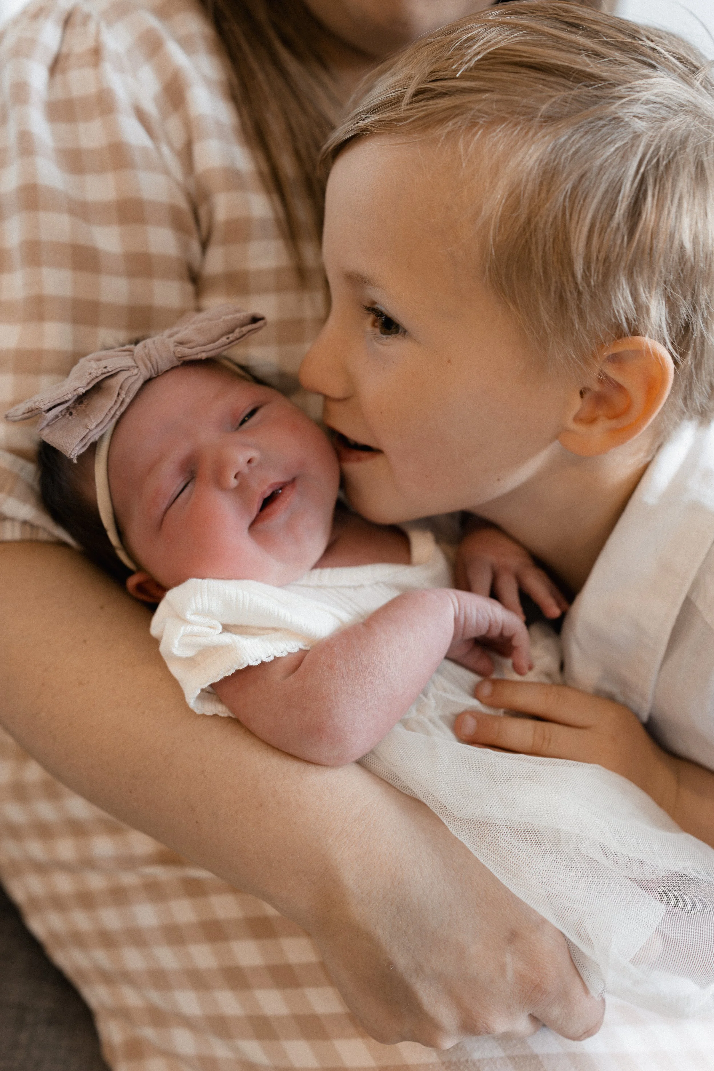older brother kissing baby sisters cheek at home