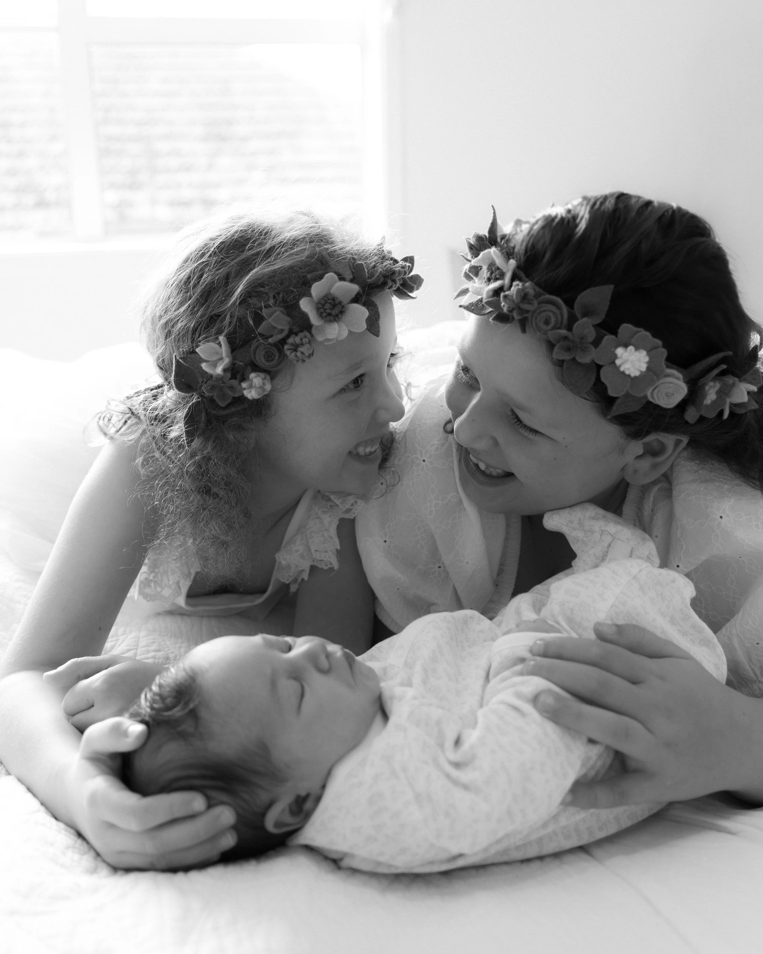 older sisters with newborn baby at home