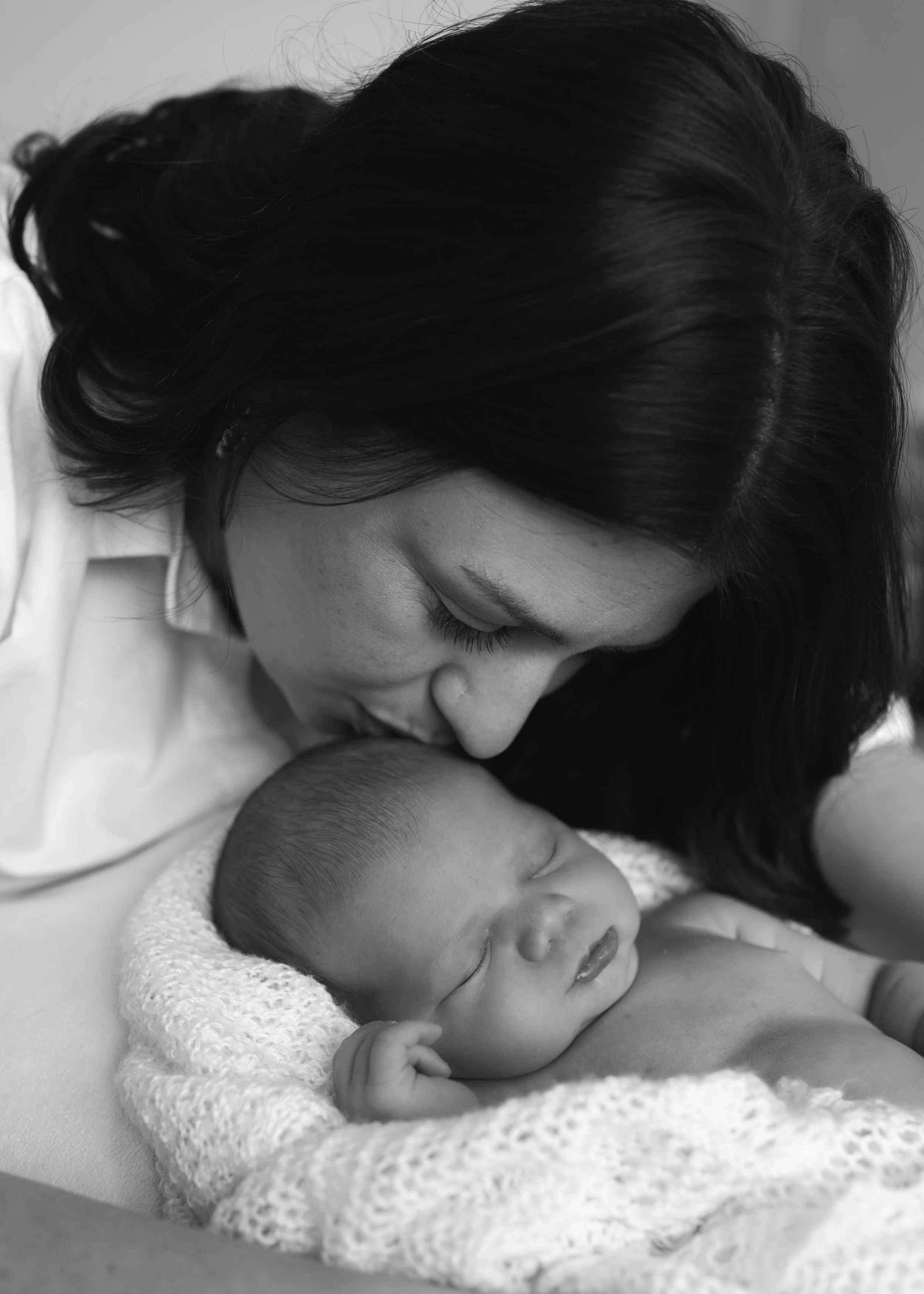 mum kissing her newborn baby at home