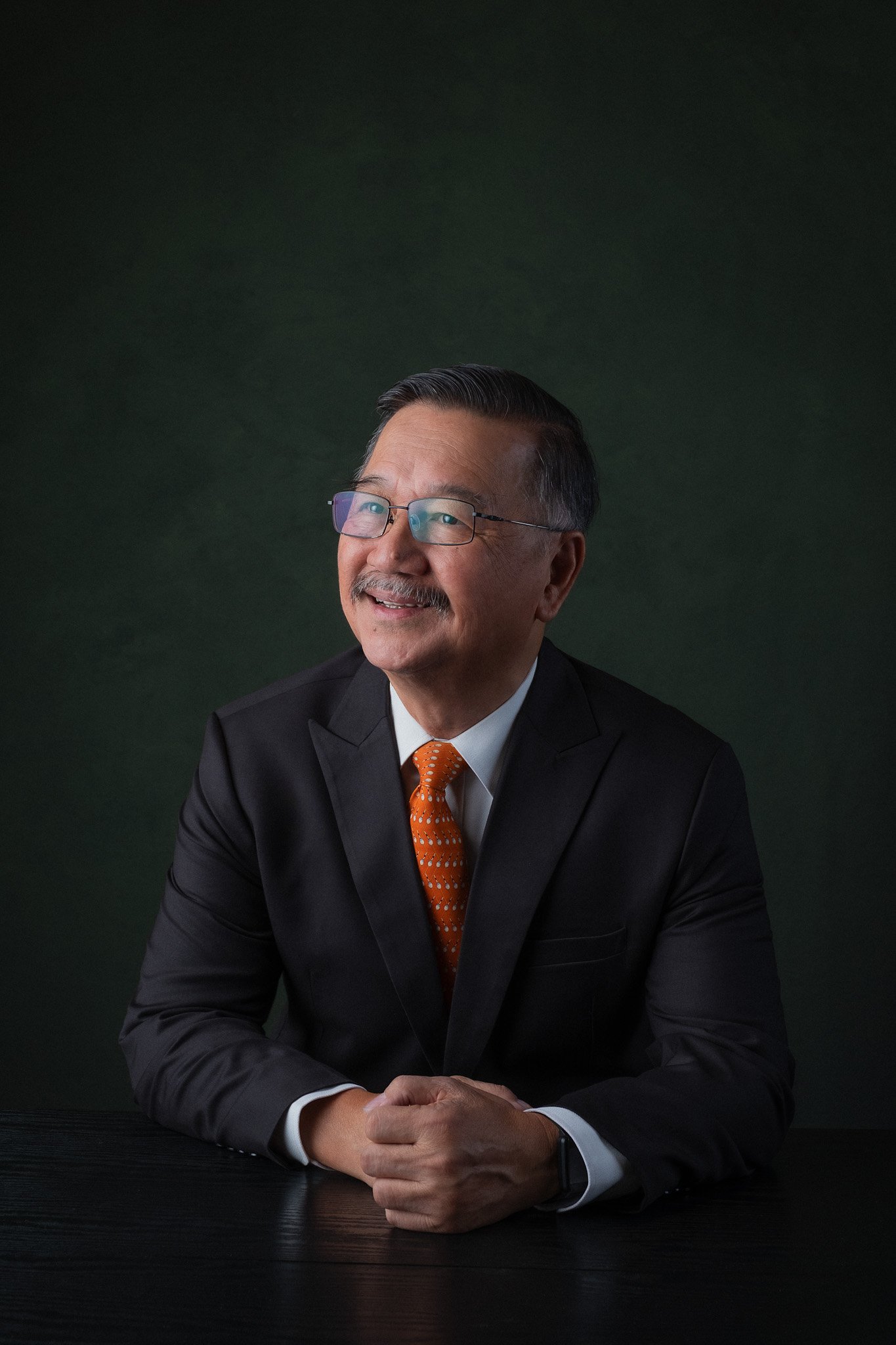 Executive portrait for Teo Cheow Tong, seated and smiling with hands in front of him. 