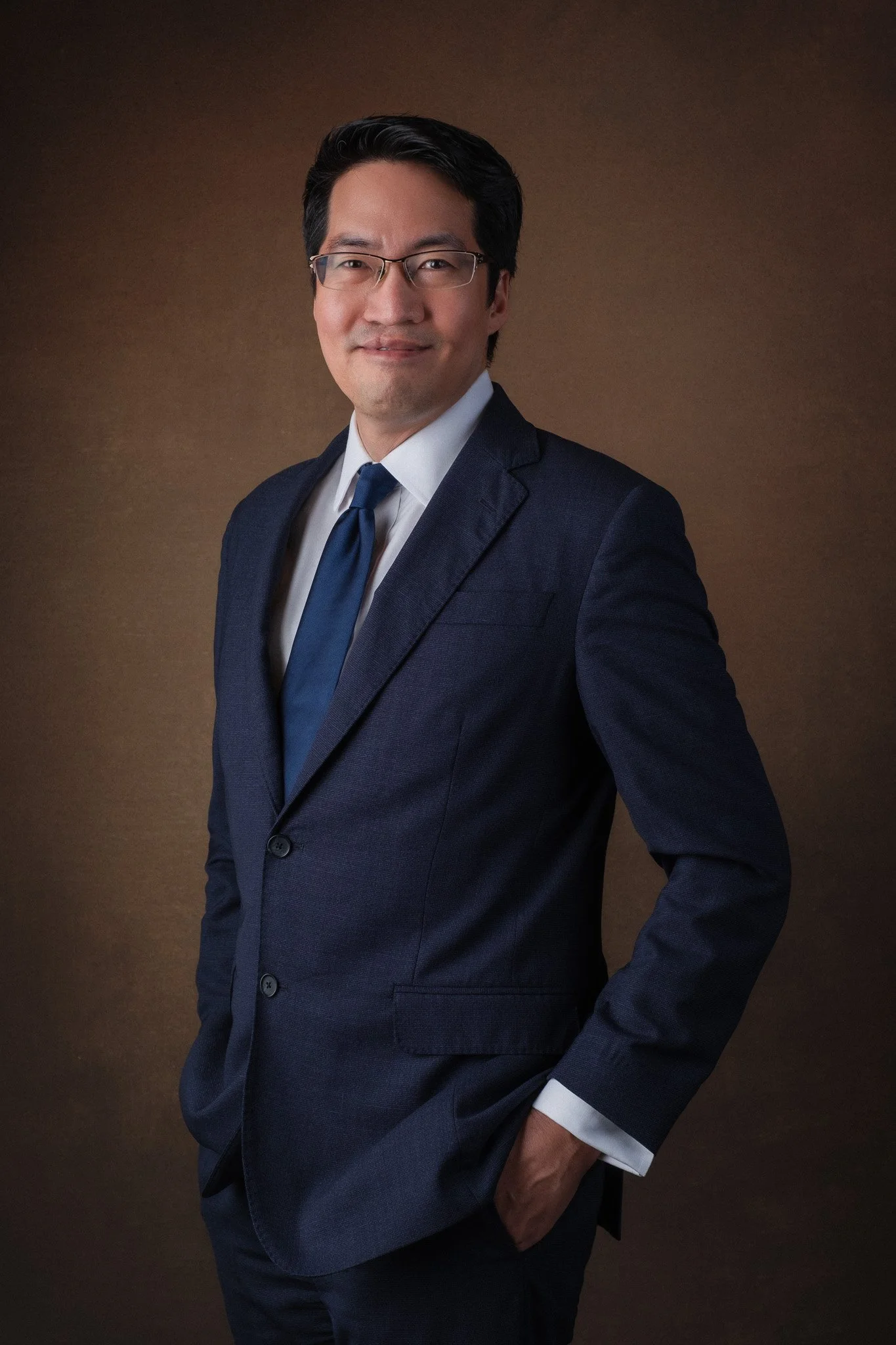 Executive portrait for Lawrence Chong, CEO of Consulus Group, TEDx Speaker and published author of several books. He is standing upright and smiling at the camera.