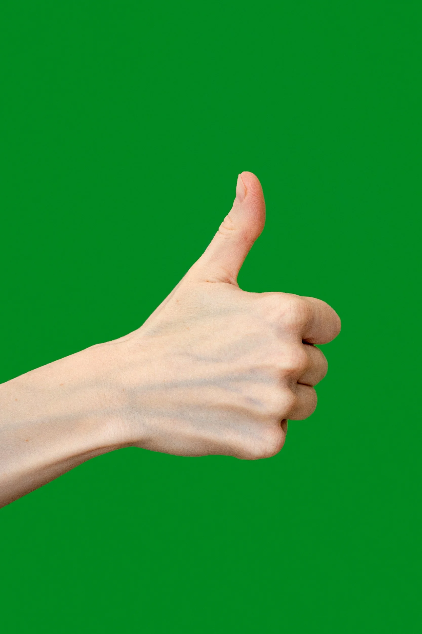 A human hand giving a thumbs-up gesture against a green background.