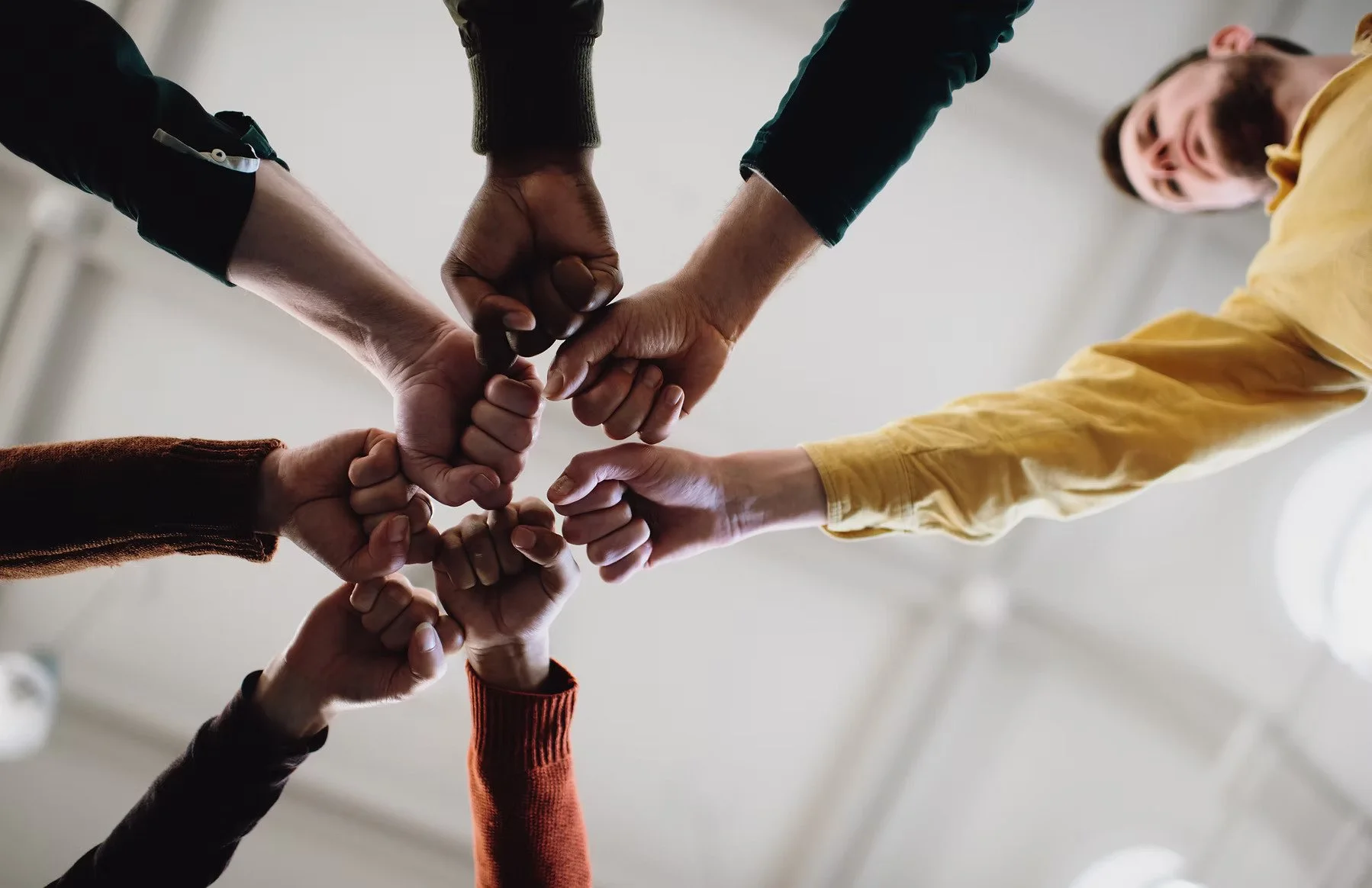 Multiple people doing a group fist bump, viewed from below.