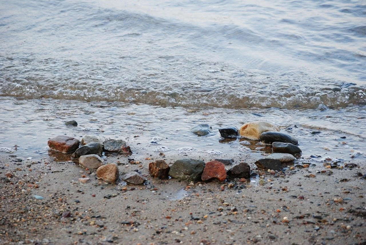 Strand mit Steinen und Sand, Wasser an der Küste