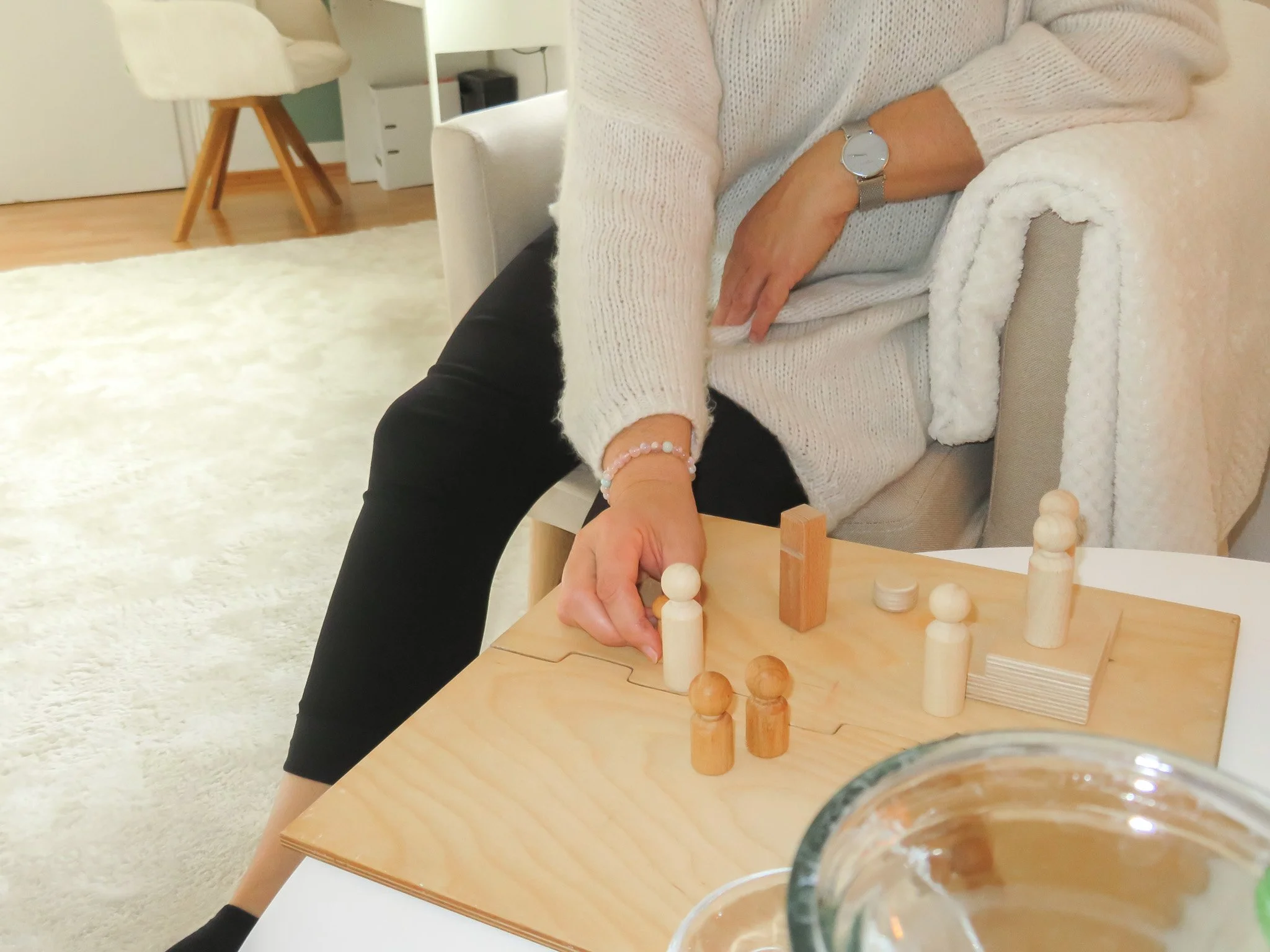 Erwachsener sitzt auf einem Sofa und macht eine systemische Aufstellung mit Holzfiguren.