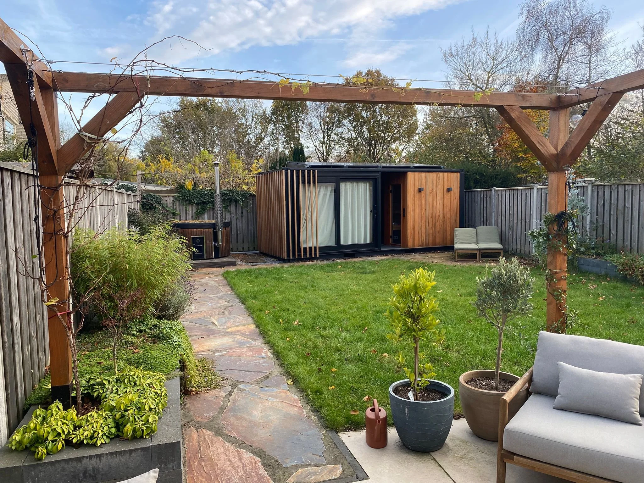 Zeecontainer achter in tuin met sauna en kantoor