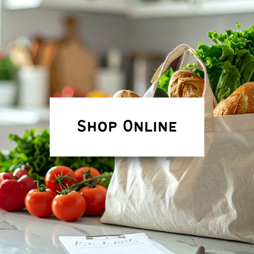 Produce and groceries in a paper bag on a kitchen countertop with tomatoes and lettuce visible.