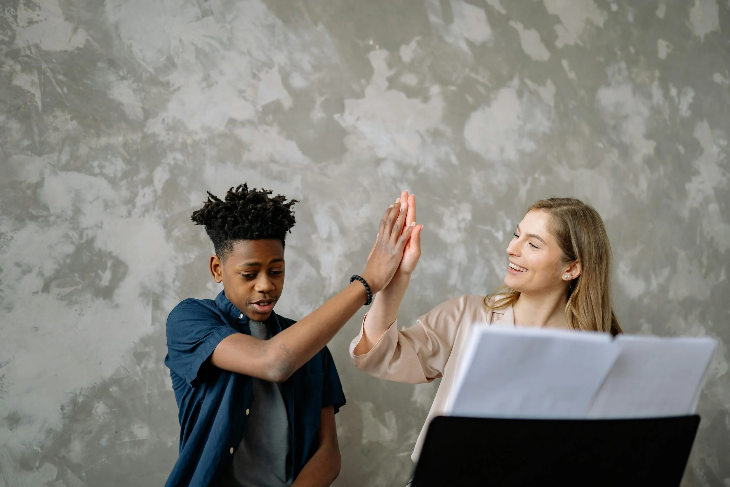 Piano teacher high-fiving a student after improving her online visibility with SEO
