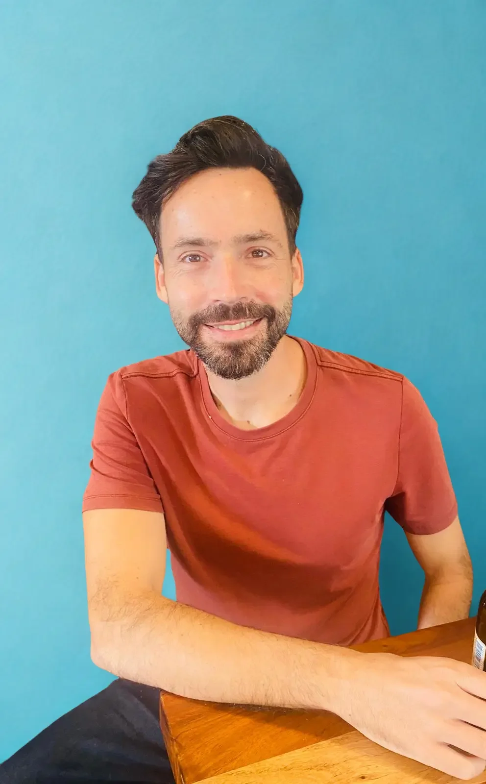 Smiling man in a casual shirt sitting at a table, used as a professional photo on an SEO services website.