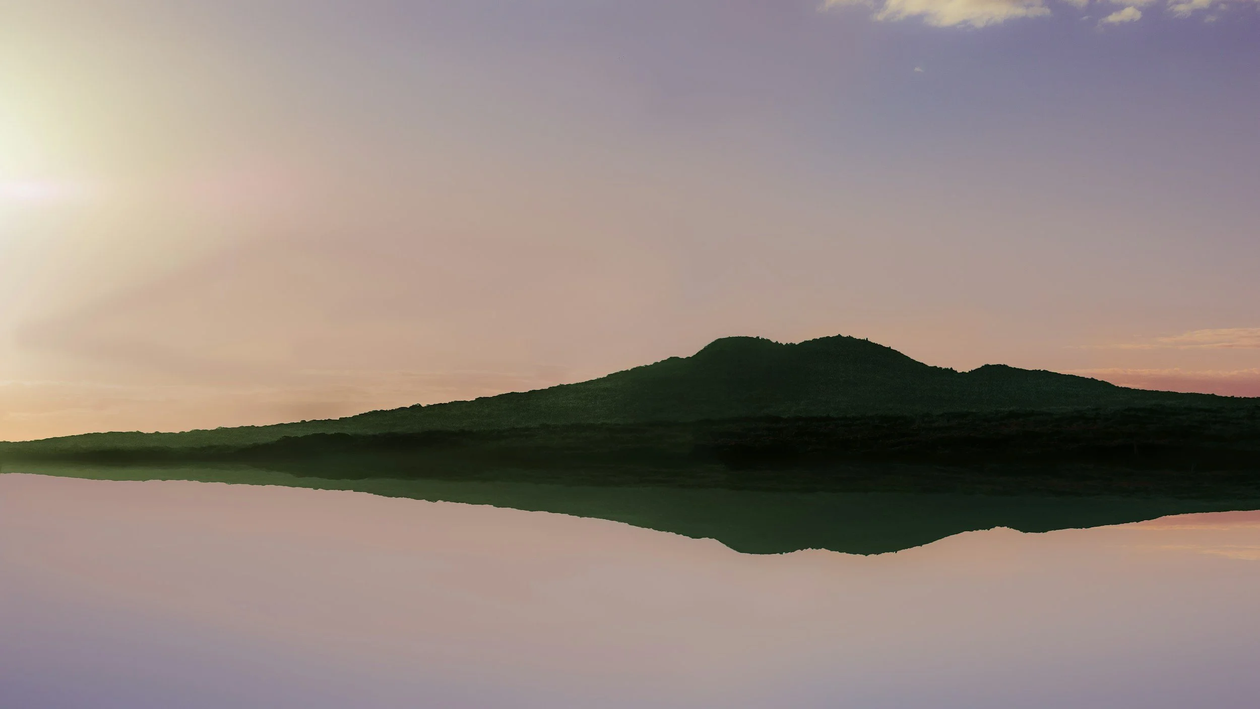 A landscape featuring a mountain with a reflection in a calm body of water, during dawn or dusk with colorful sky.