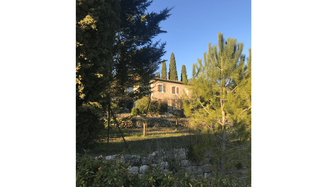 Colette Ozanne doula Kennington, Provence, cypresses, garden and house on a suuny day with a little stone wall at the front
