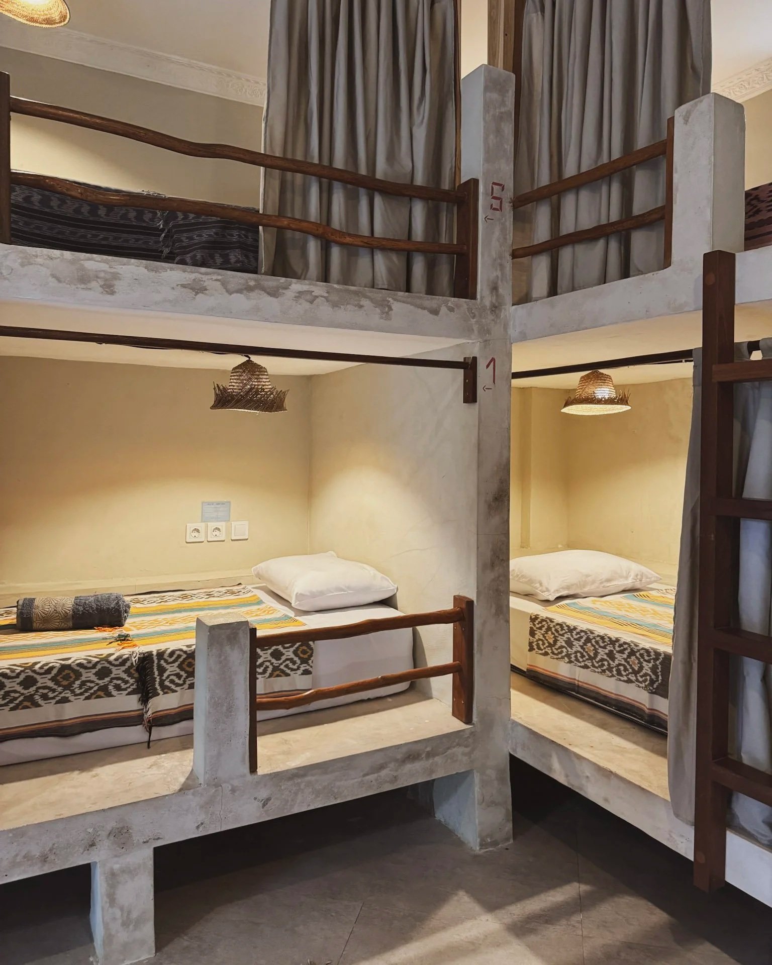 Bunk beds with two lower beds and two upper beds in a cozy room, with bedside lamps, towels, and pillows.