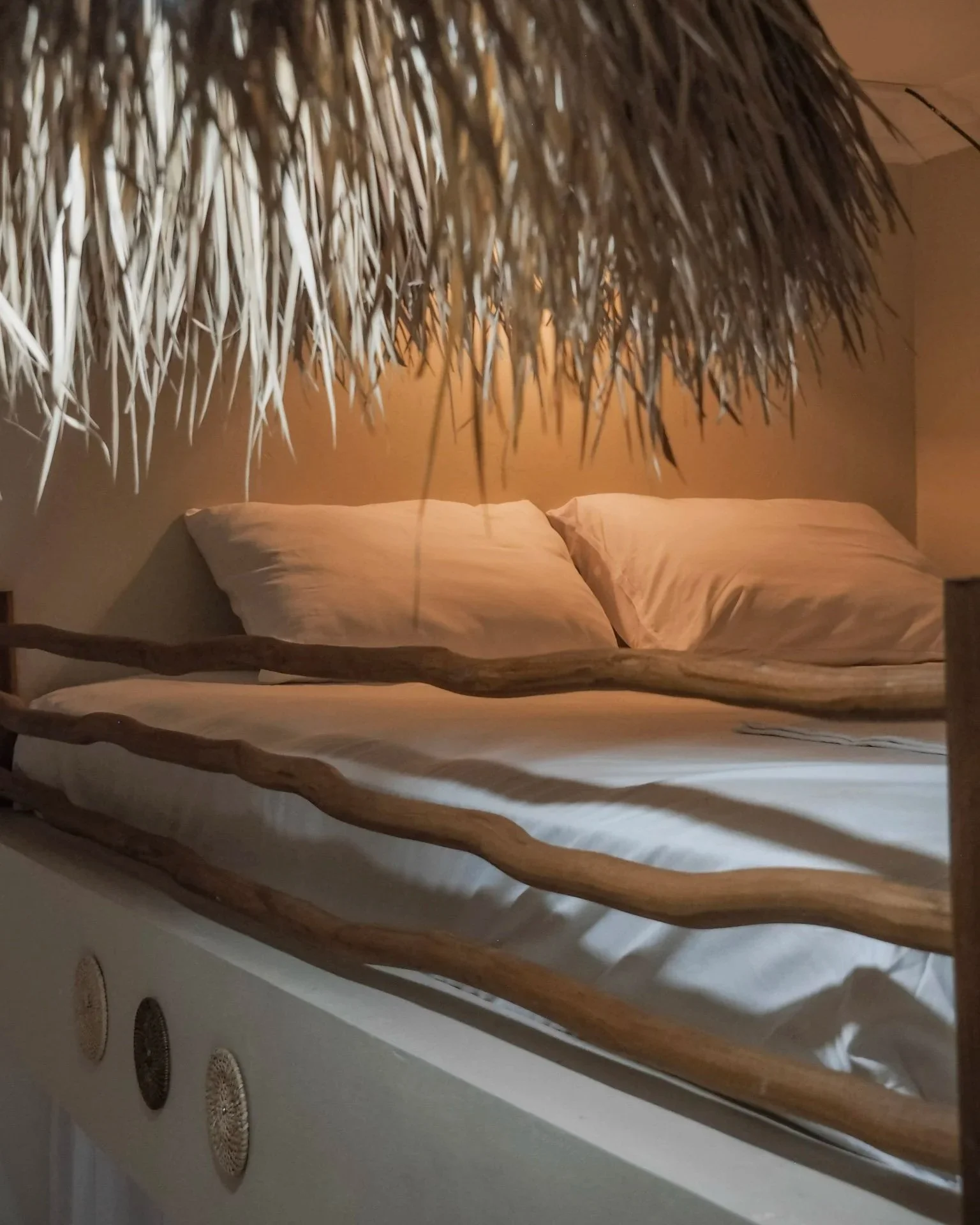 Close-up of a thatched roof over a bed with pillows in a cozy bedroom