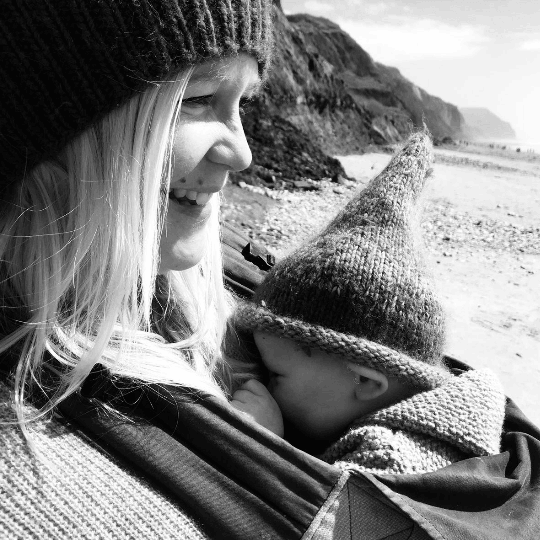 Harriet Symon with baby in a sling on the beach