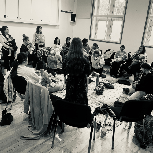 Women and babies at Early mothering postnatal group in Larkhall at New Oriel Hall, sitting in a circle, rocking, breastfeeding and chatting