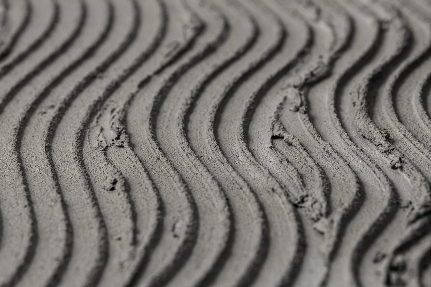 Close-up of textured sand with wavy patterns.