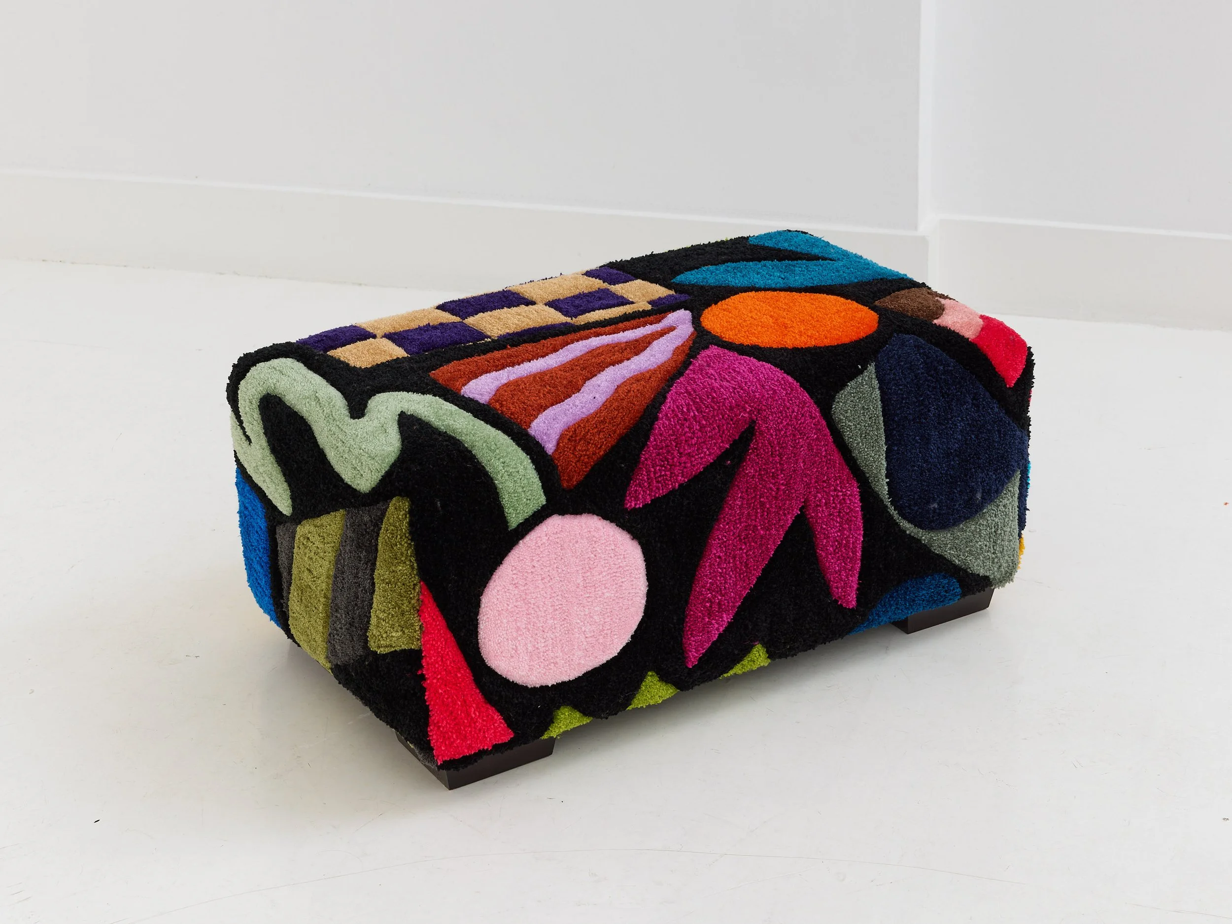 Colorful upholstered stool with abstract floral and geometric patterns on a white surface
