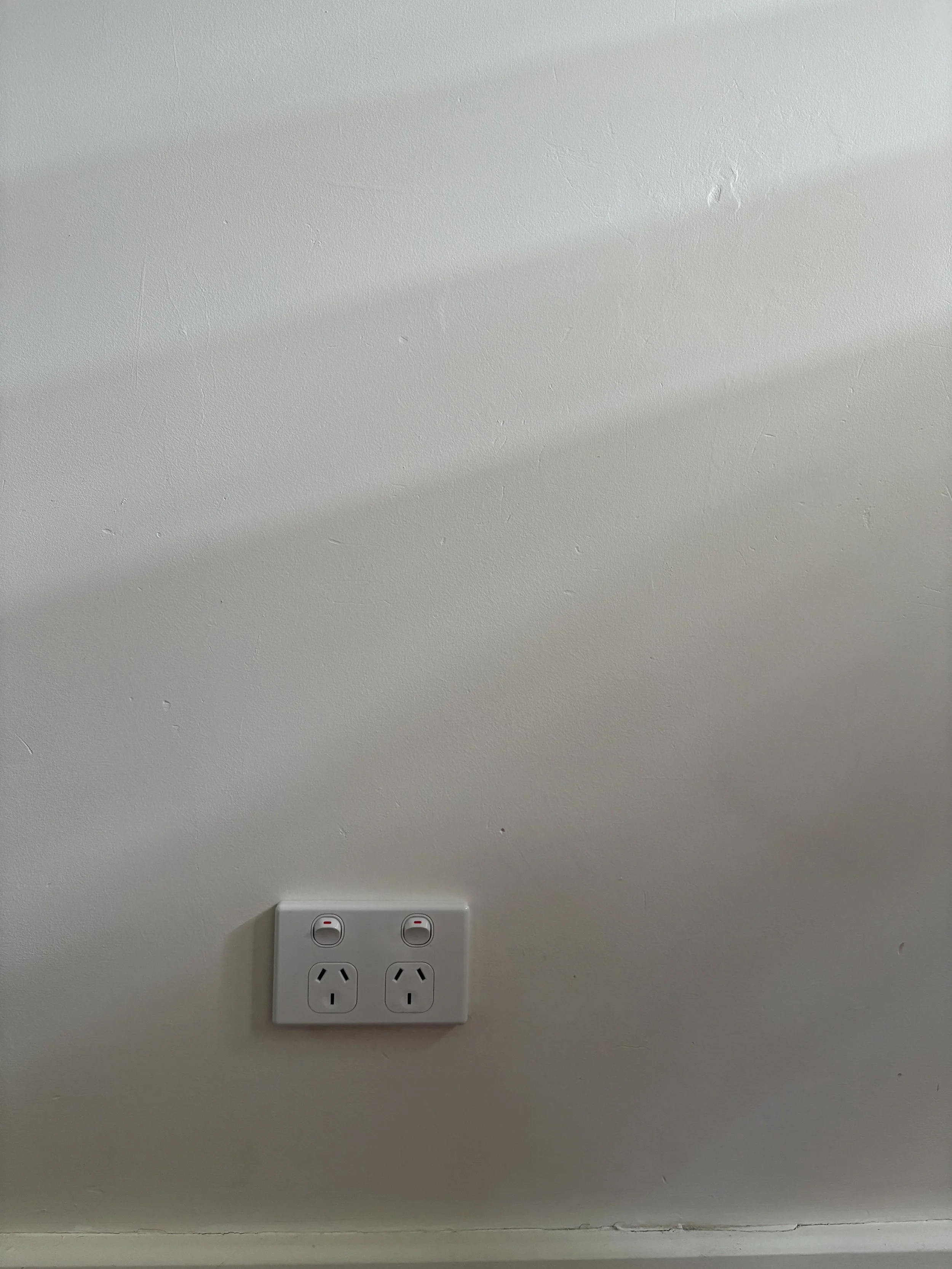White wall with a double electrical outlet and power switches.