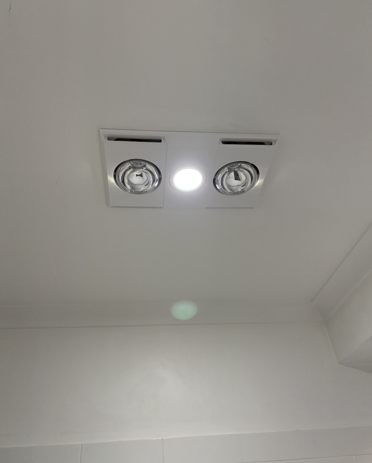 Ceiling light fixture with two adjustable spotlights and a central recessed light in a white ceiling.