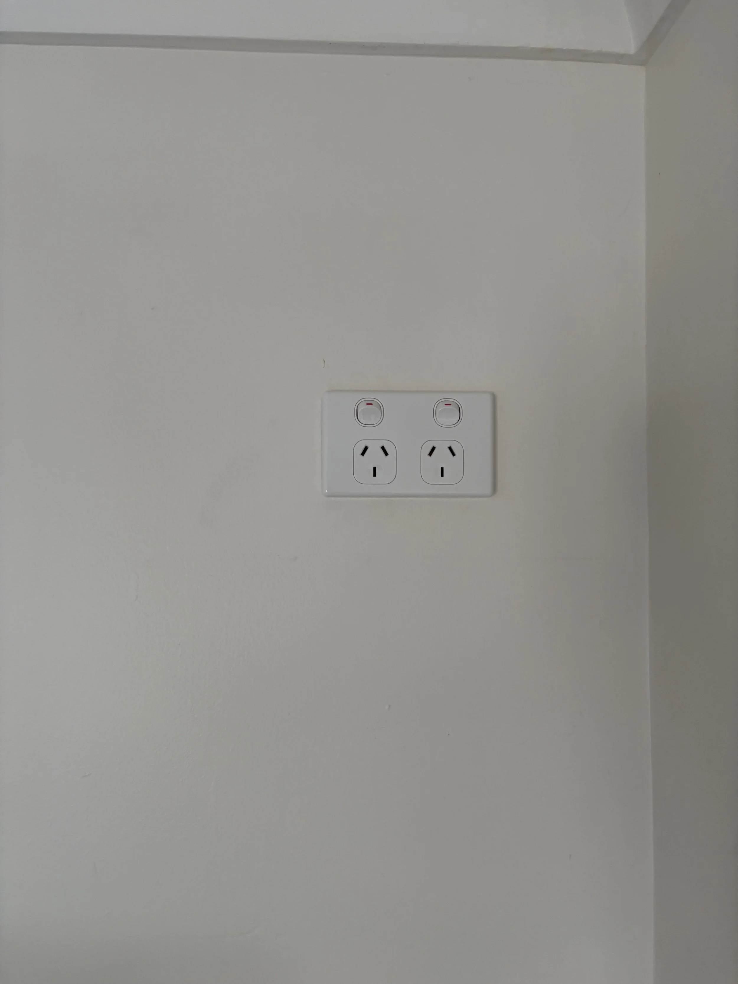 White wall with double power outlets and two switches.