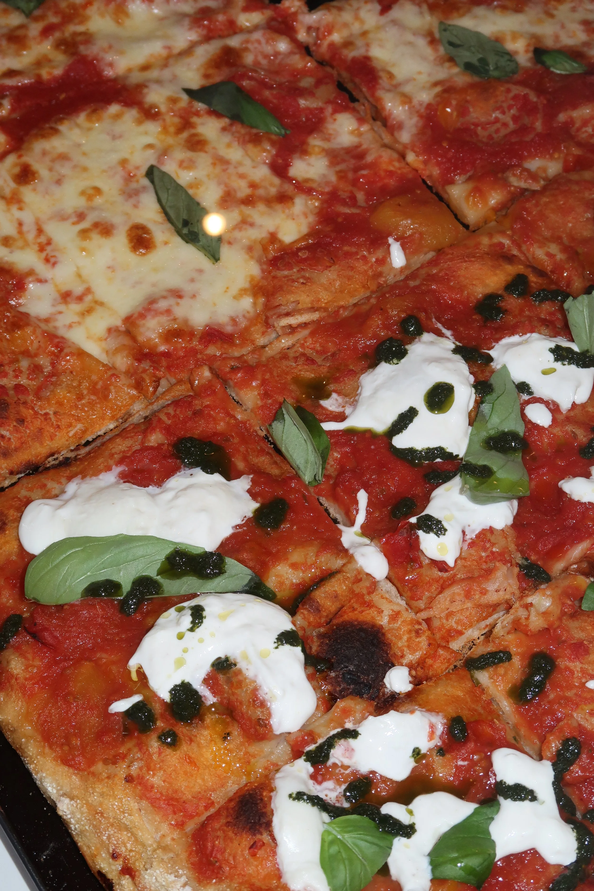 Mehrere Stücke Pizza mit Tomatensoße, Käse, Basilikum, Ricotta, schwarzen Oliven und ggf. Basilikum