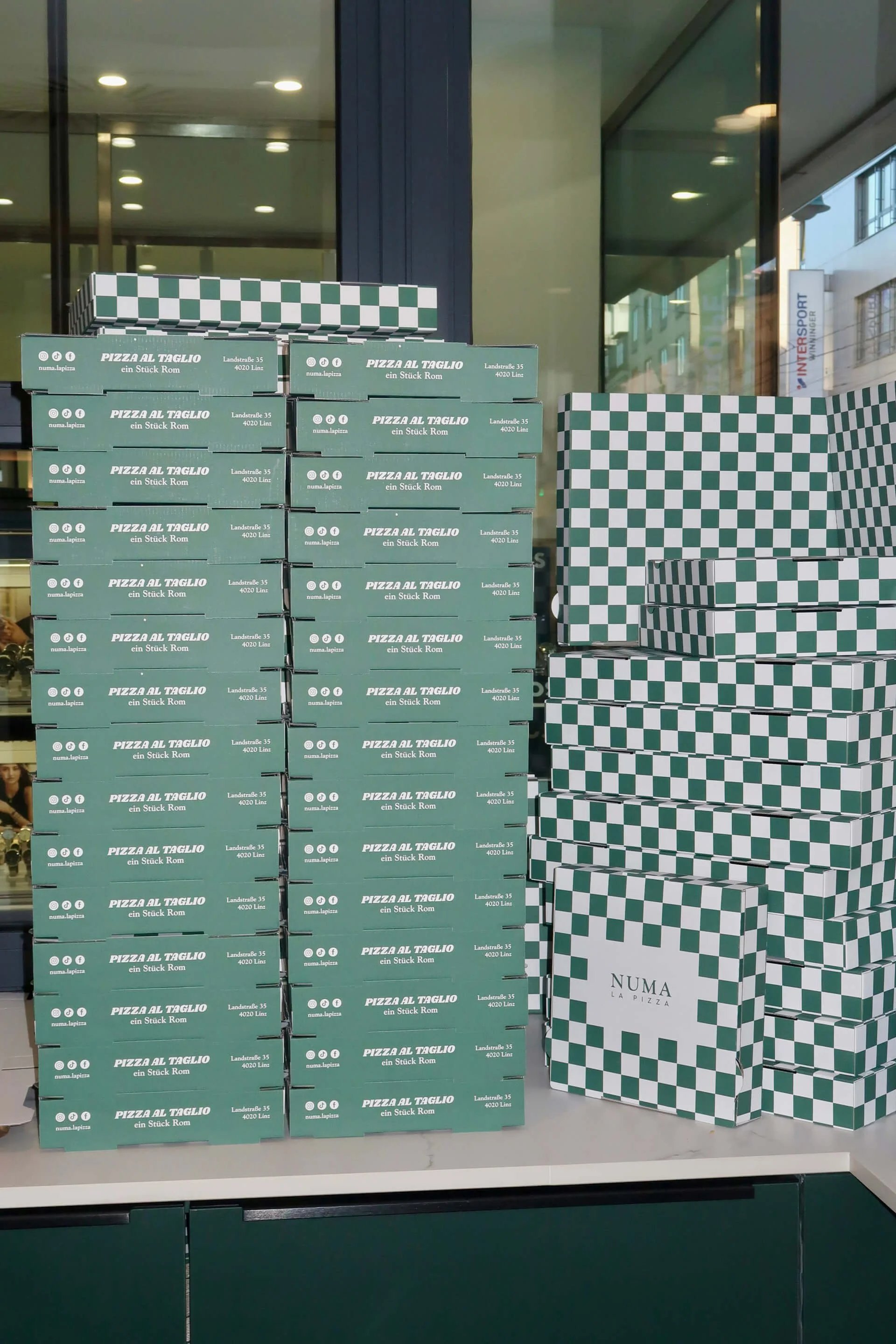 Gestapelte NUMA Pizzaboxen im Lokal auf der Landstraße in Linz