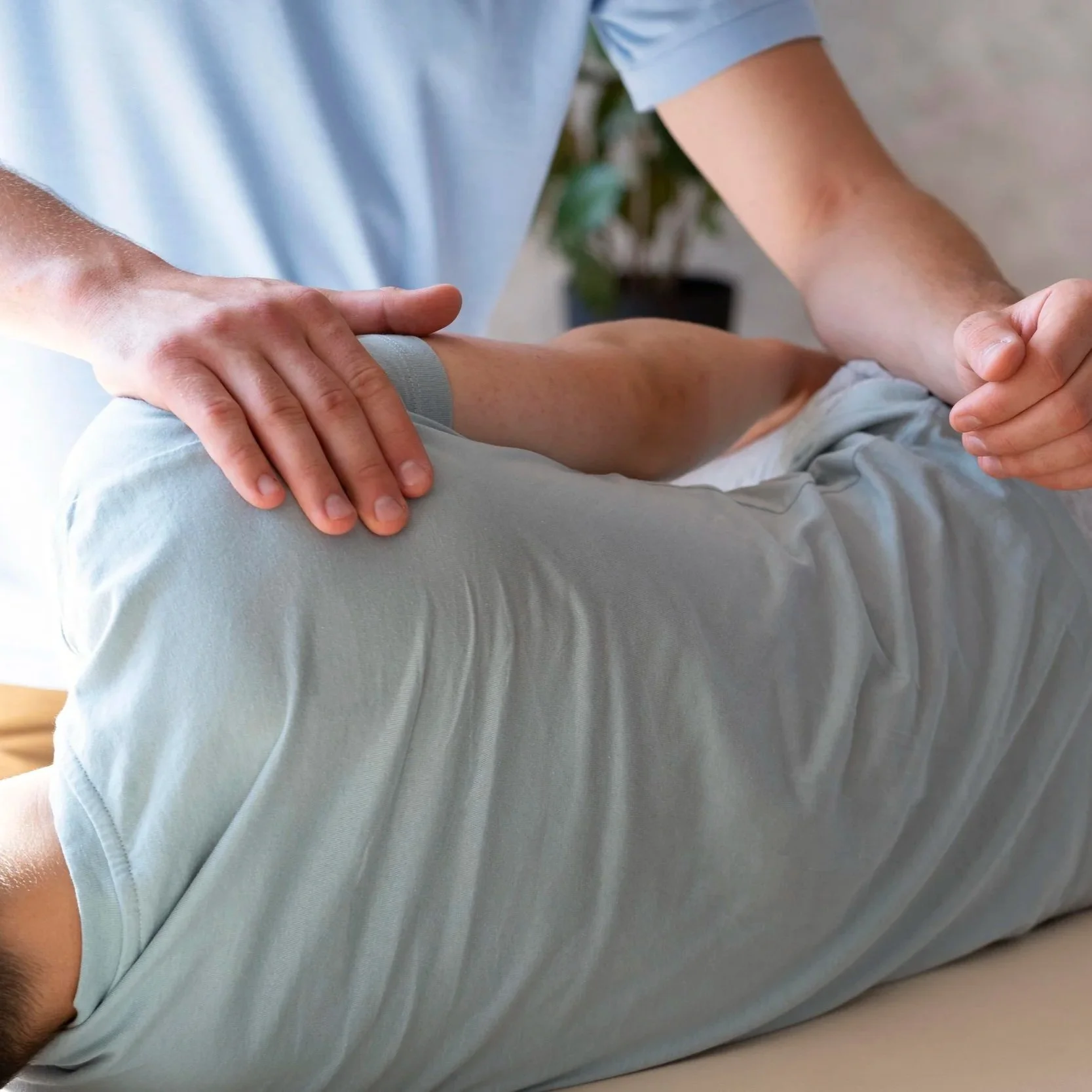 A healthcare professional performs a physical therapy or medical examination on a patient's arm and torso, who is lying on a treatment table.