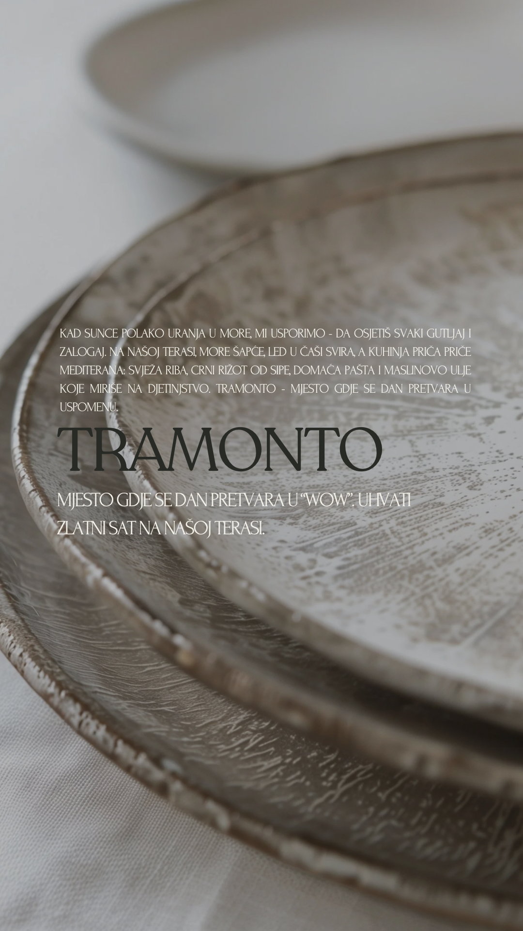 Close-up of decorative silver trays with textured surfaces, stacked on a light-colored tablecloth, with overlaid text describing a place called Tramonto.