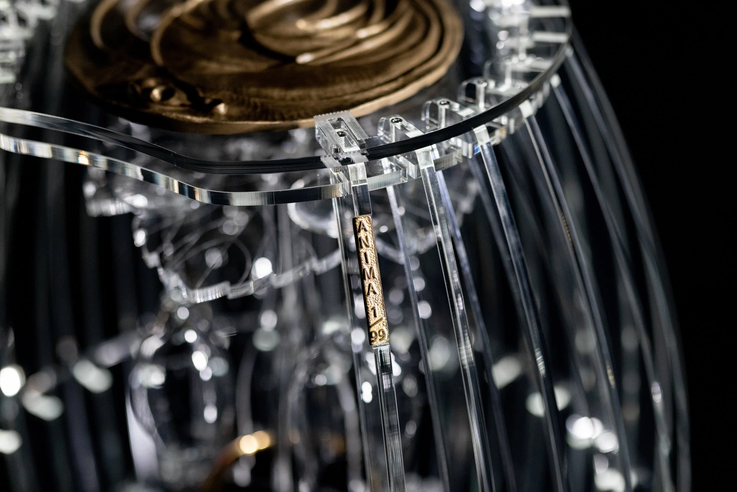 Dettaglio di "Anima", un'opera d'arte numerata a forma di botte realizzata in plexiglass con una targhetta numerata, e una spirale di bronzo, con supporti e centine trasparenti e parti riflettenti.