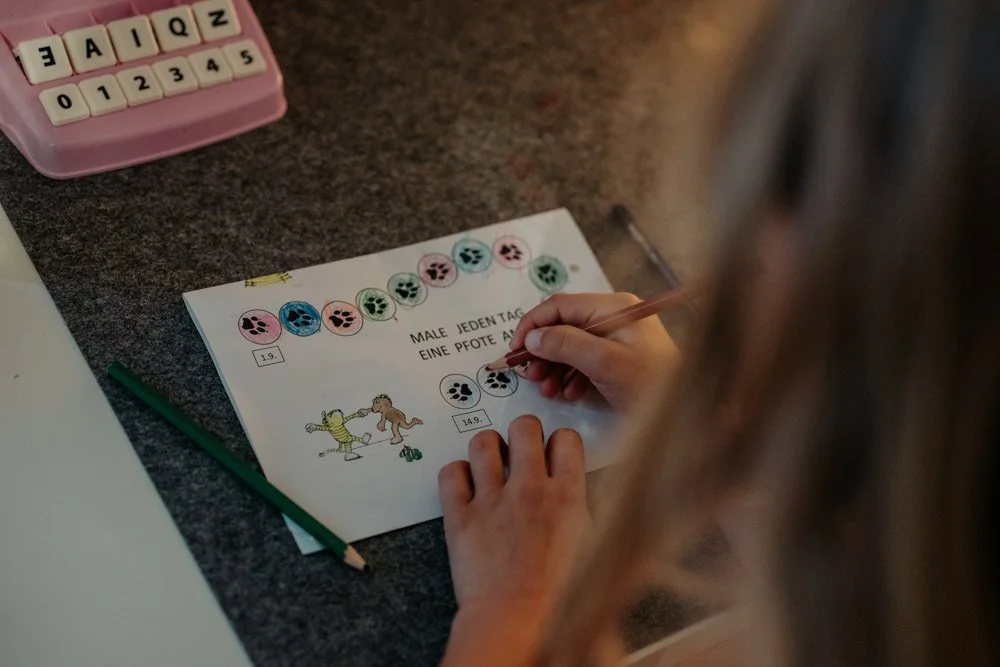 Ein Kind malt Fußabdrücke auf einem Blatt Papier aus, welche die letzten Tage vor dem ersten Schultag symbolisieren.