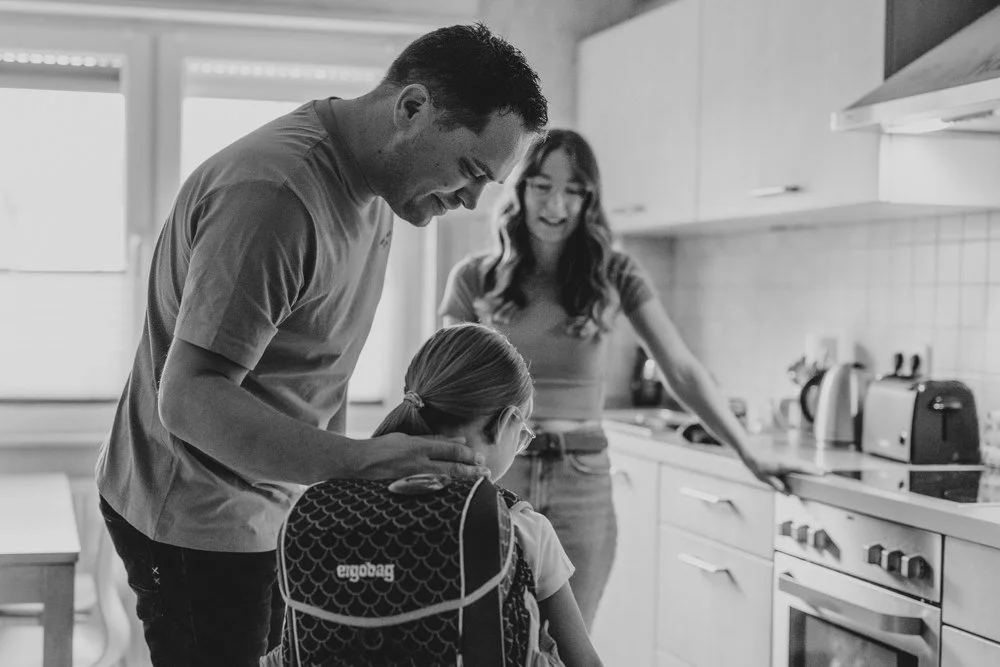 Eine Familie erlebt einen emotionalen Moment, als das Kind mit Schultüte und Schulranzen in der Küche steht, fotografiert von einer Fotografin aus Mannheim.