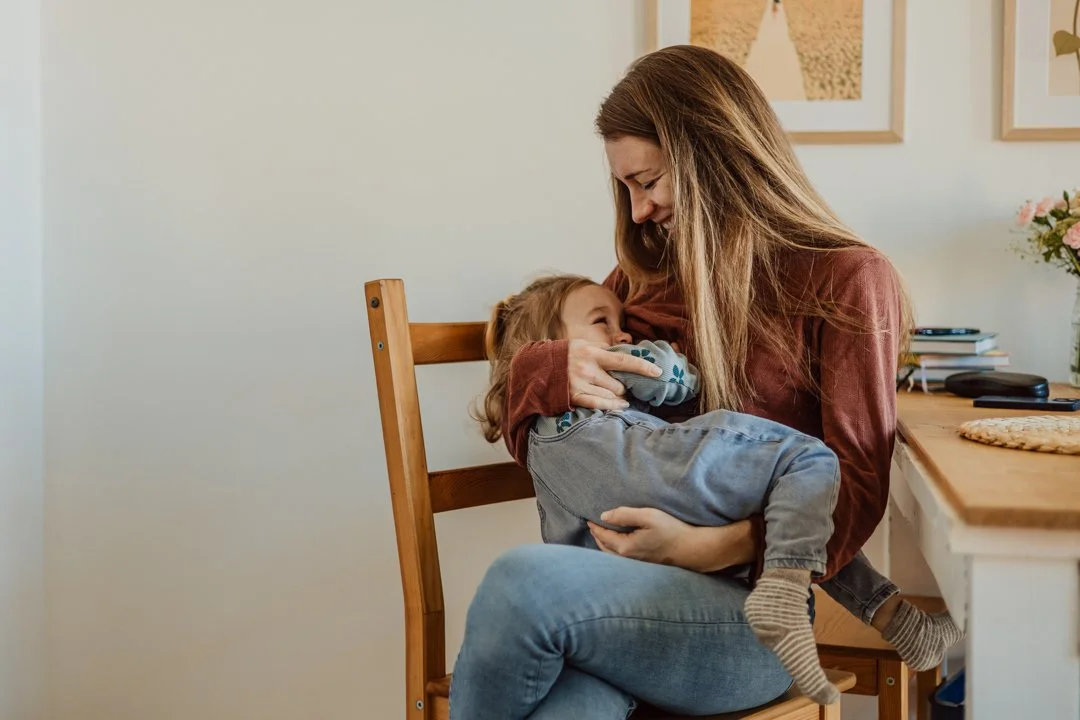 Natürliche Familienfotografie zeigt eine Mutter mit ihrer Tochter im Arm.